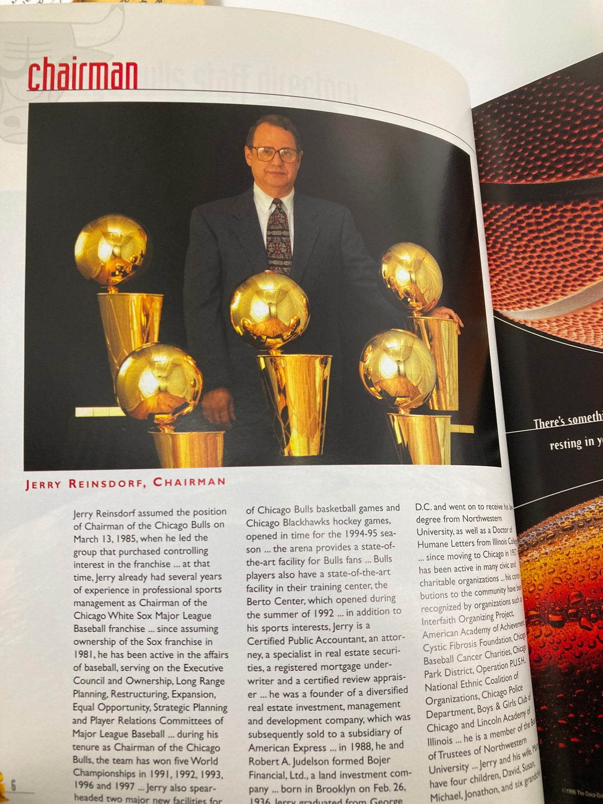 Portrait of Jerry Reinsdorf, Chairman of the Chicago Bulls, standing with five championship trophies featured in the NBA Chicago Bulls Official 1997 - 1998 Yearbook.