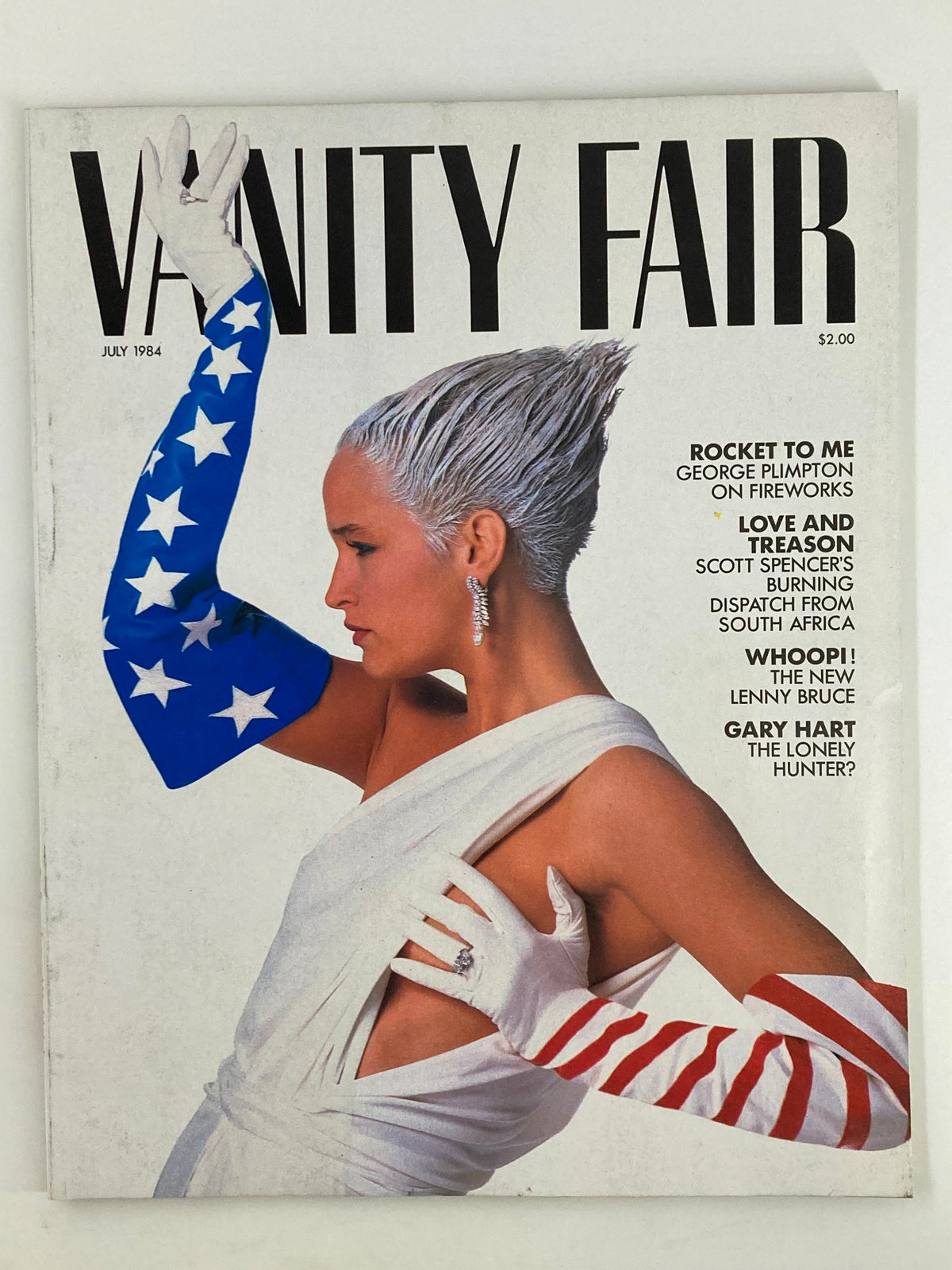 Cover of the VTG Vanity Fair Magazine July 1984 featuring the article 'Rocket to Me' by George Plimpton, showcasing a model in a striking pose wearing gloves with patriotic designs.