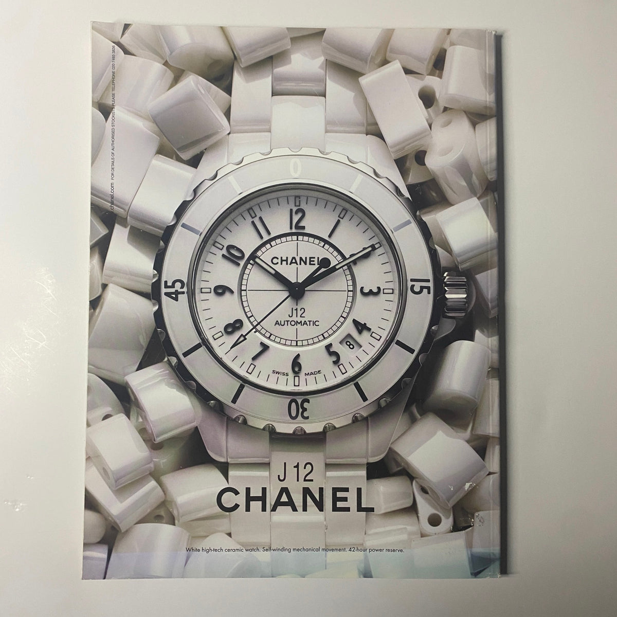 Chanel J12 Automatic watch featured in Harper's Bazaar Magazine June 2010. The watch is presented against a backdrop of white accessories, showcasing its elegant design.