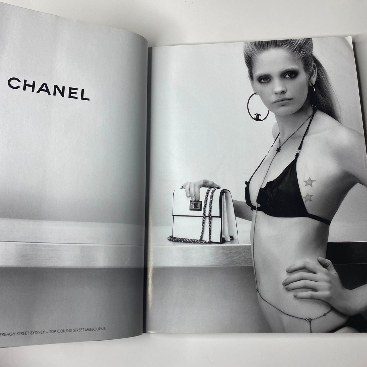 Chanel advertisement featuring a model in a black bikini posing with a handbag, showcasing the brand's elegant style. From Harper's Bazaar Australia Magazine, December 2008, Nicole Kidman Cover (No Label, VG Condition).