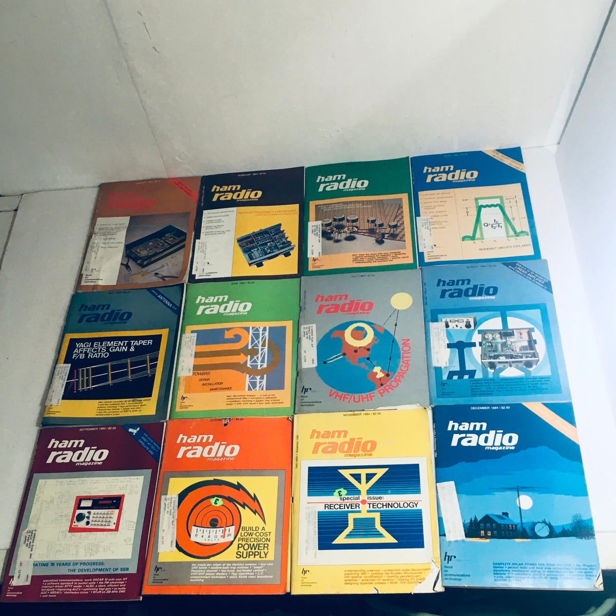 Lot of 12 Complete January to December 1984 Ham Radio Volume 1 to 12, displaying colorful magazine covers featuring various ham radio topics and technologies.