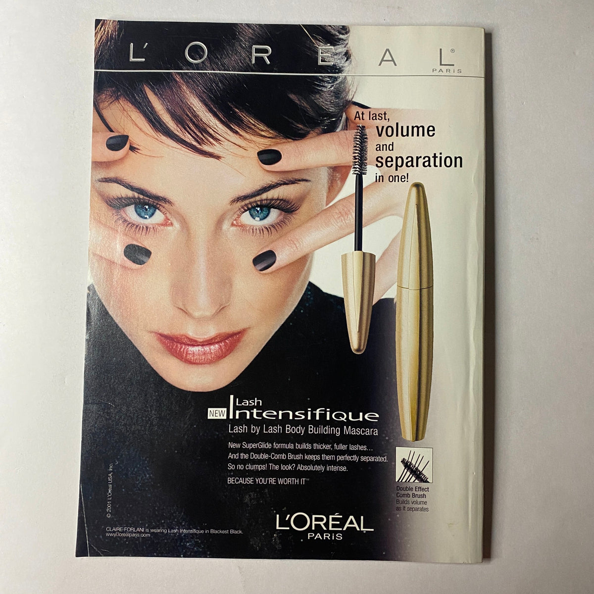 L'Oreal Paris mascara advertisement featuring a model with striking makeup, promoting Lash Intensifique mascara for volume and separation, in Vogue Magazine January 2002 issue with Julianne Moore cover.