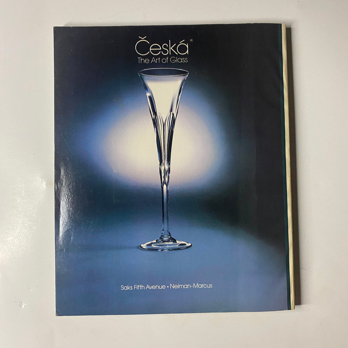 Cover of Česka: The Art of Glass catalog, featuring an elegant crystal glass against a soft blue background, highlighting luxury glassware available at Saks Fifth Avenue and Neiman-Marcus.
