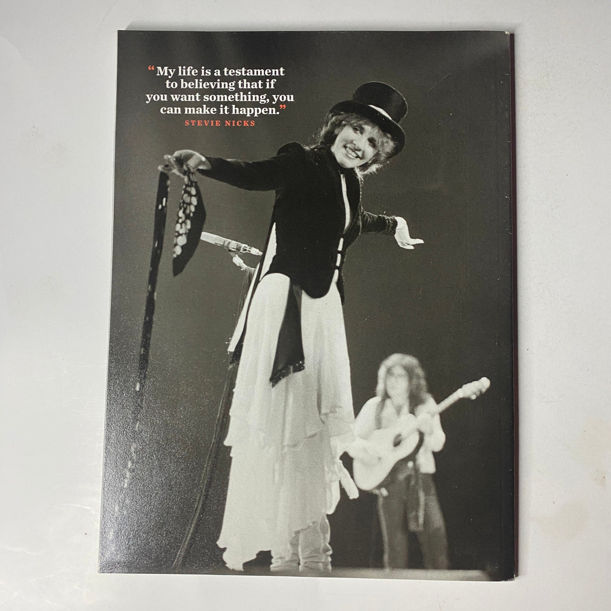 Stevie Nicks performing on stage, wearing a signature top hat and coat, with the quote 'My life is a testament to believing that if you want something, you can make it happen.' Featured in the Stevie Nicks Magazine January 02 2023 Photo Book.