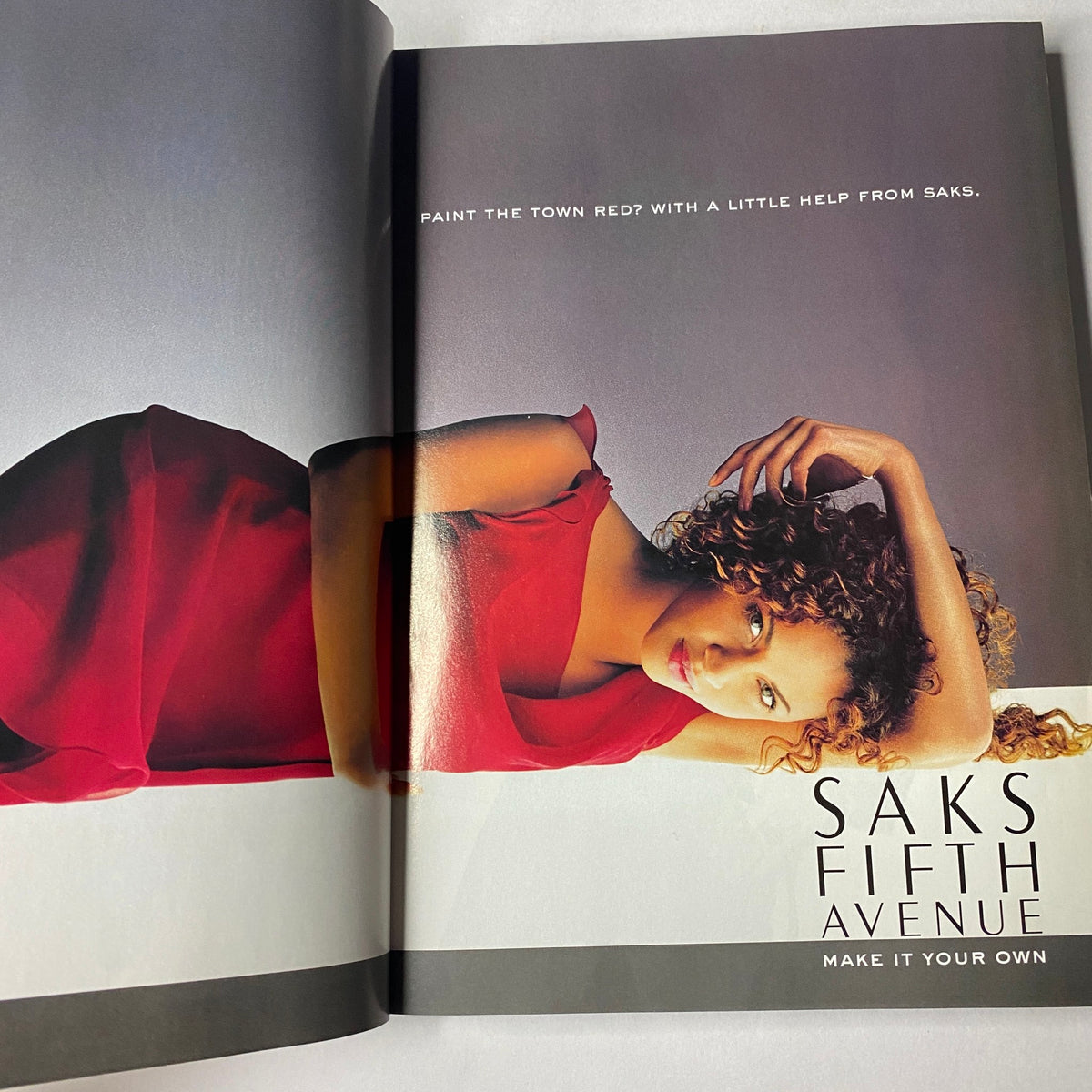 Fashion advertisement featuring a model in a red dress for Saks Fifth Avenue, showcasing the tagline 'Paint the Town Red? With a Little Help from Saks' in the Vogue Magazine November 2002 Catherine Zeta-Jones & Renée Zellweger issue.