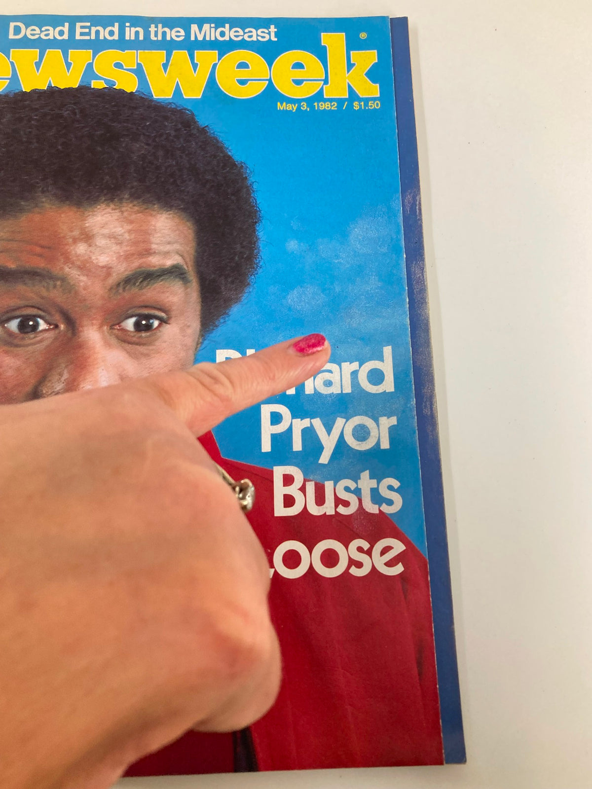 Close-up of the Newsweek magazine cover from May 3, 1982, showcasing Richard Pryor and highlighting the title 'Richard Pryor Busts Loose' with a finger pointing towards the text.