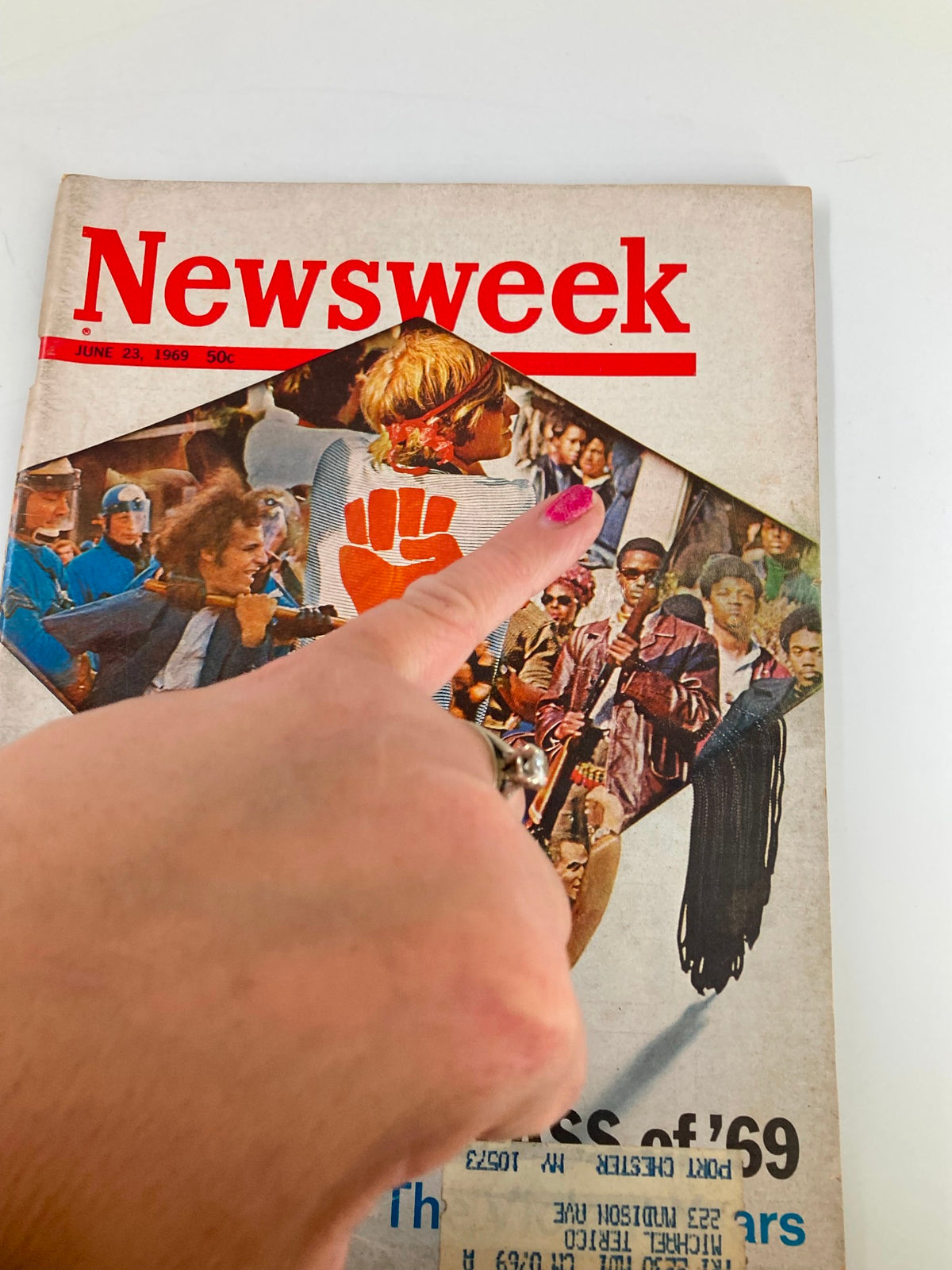 Close-up of the vintage Newsweek magazine cover from June 23, 1969, 'The Class of '69: The Violent Years,' with a hand pointing at the artwork, highlighting the protest elements.
