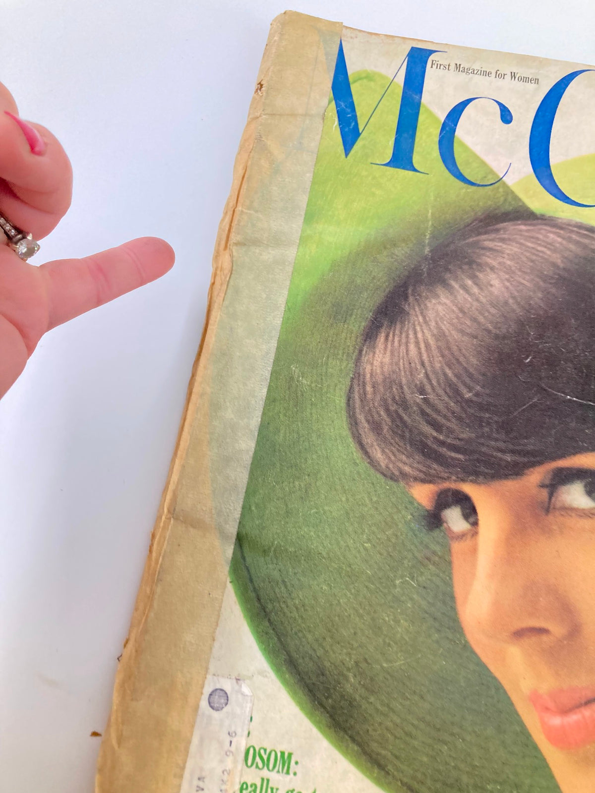 Close-up detail of the side edge of the vintage McCall's Magazine March 1965 cover featuring Tilly Tizzani by O. Storch, highlighting the magazine's wear and tear.