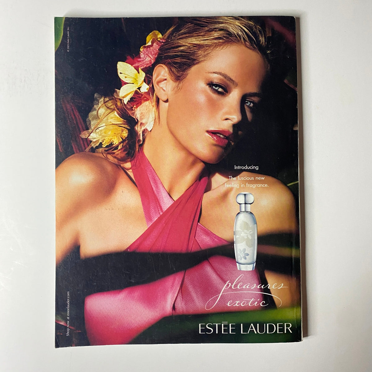 Vogue Magazine July 2005 advertisement page introducing Estée Lauder's Pleasures Exotic fragrance, featuring a glamorous model with floral accents.