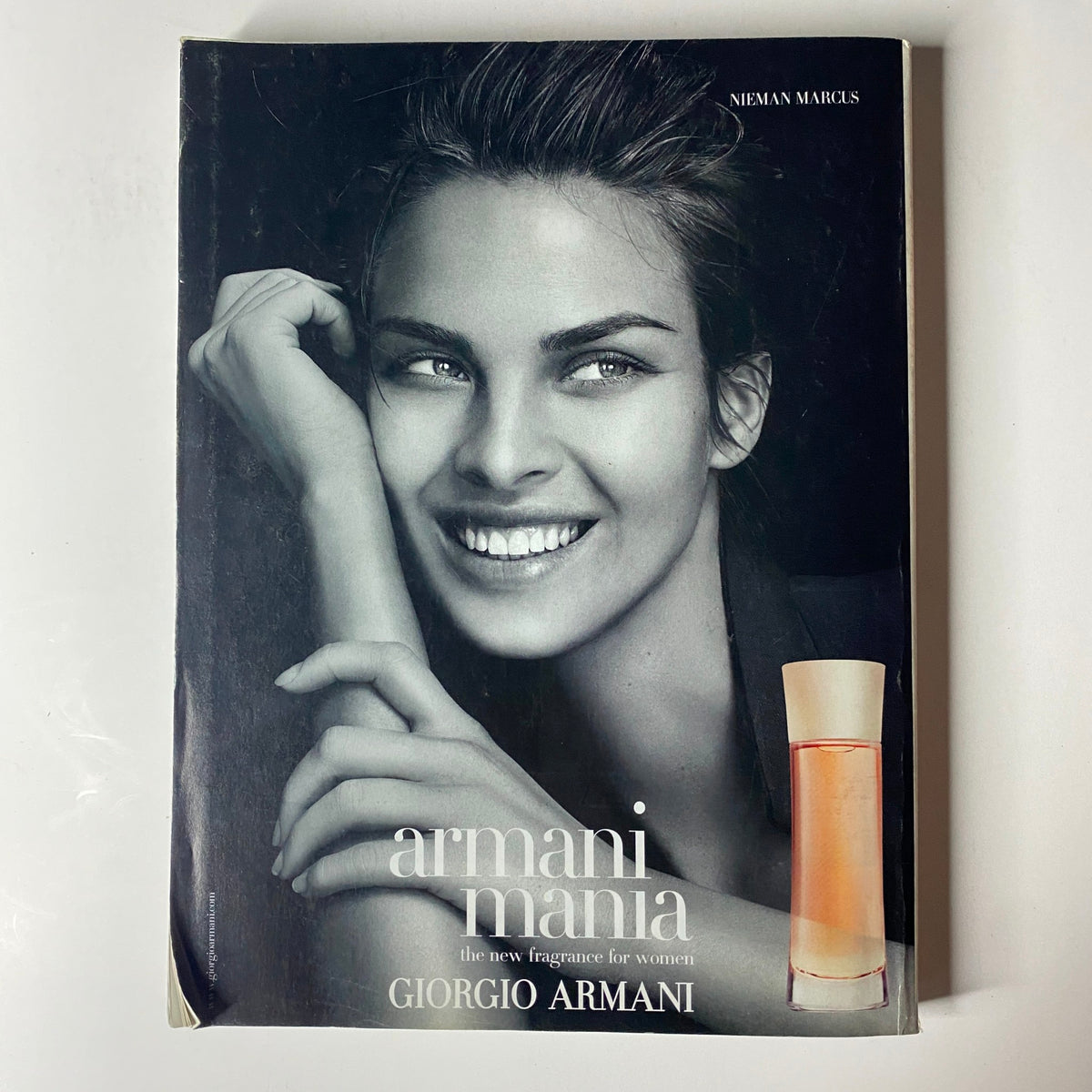 Image of Giorgio Armani fragrance advertisement featuring a smiling model. The advertisement promotes 'armani mania' perfume for women, highlighting its elegance and sophistication, as seen in Vogue Magazine November 2004 with Jennifer Connelly on the cover.