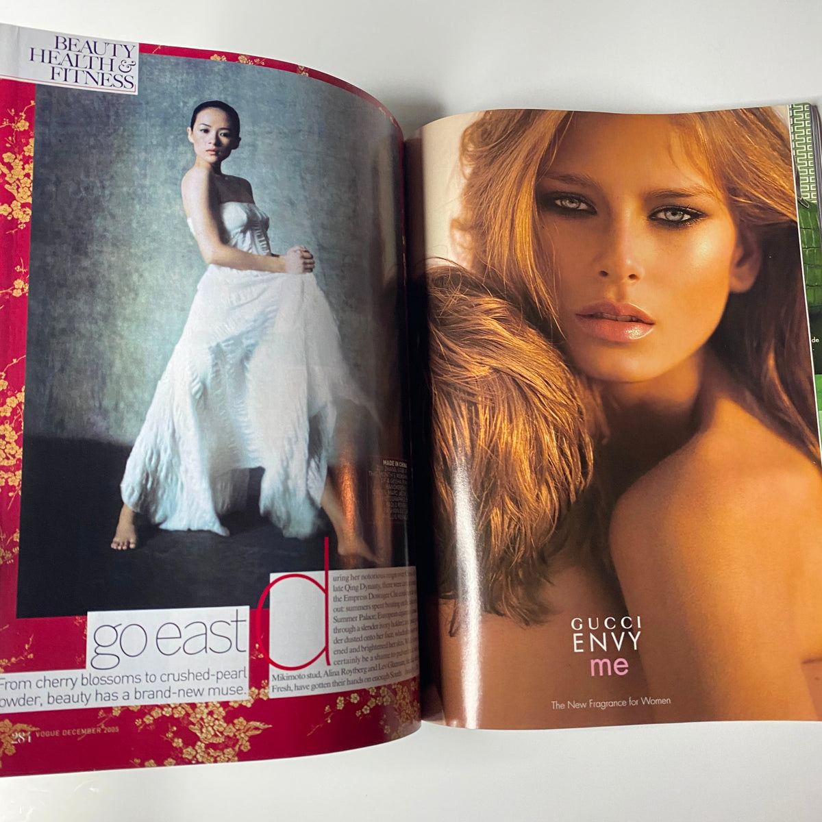 Fashion editorial spread featuring beauty and health highlights from Vogue Magazine December 2005 Keira Knightley Cover. Showcases 'Go East' beauty article alongside a Gucci fragrance advertisement.