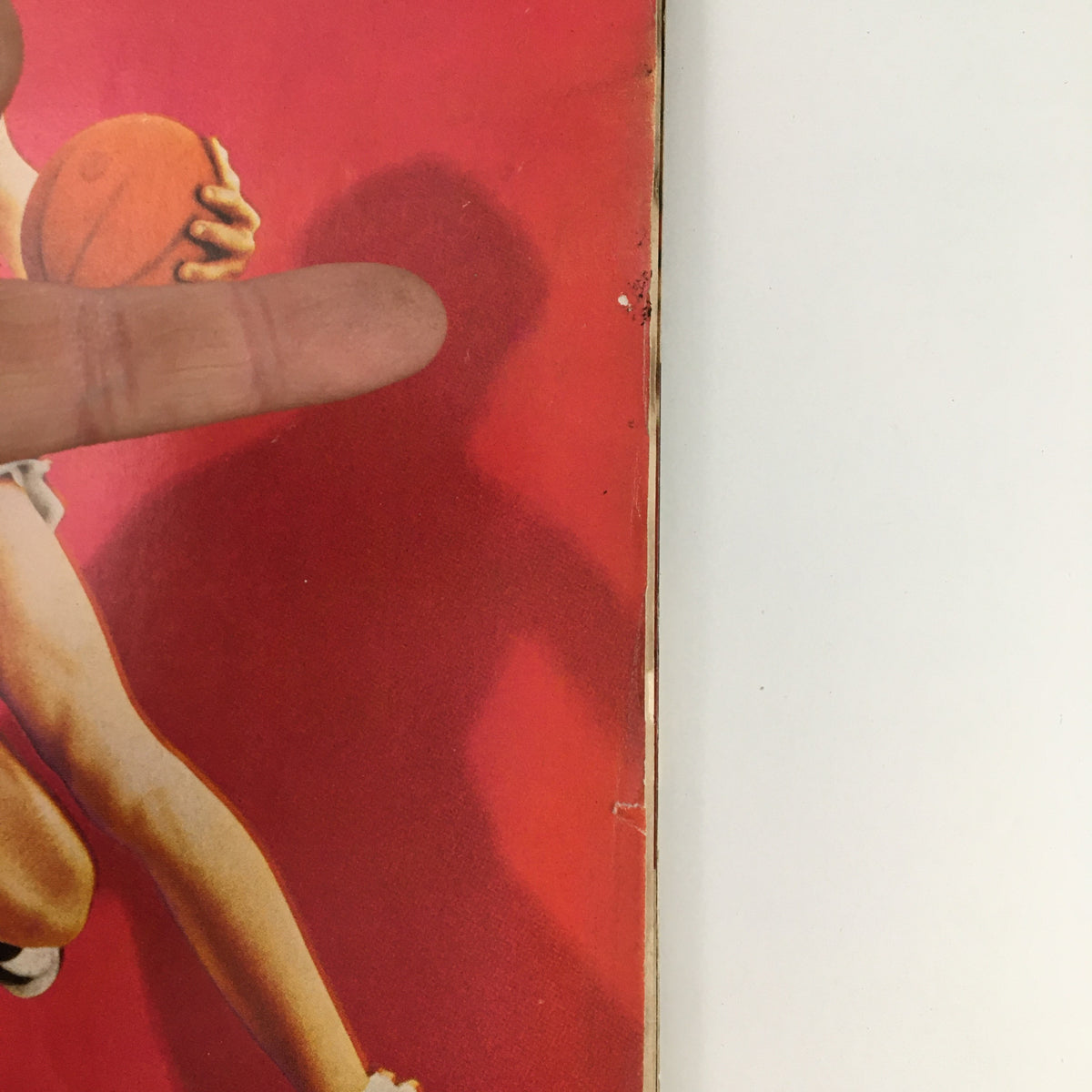Close-up of the cover of Sports Illustrated Magazine December 1 1969, highlighting Pistol Pete Maravich, with a hand pointing towards the magazine cover, emphasizing its vintage appeal.