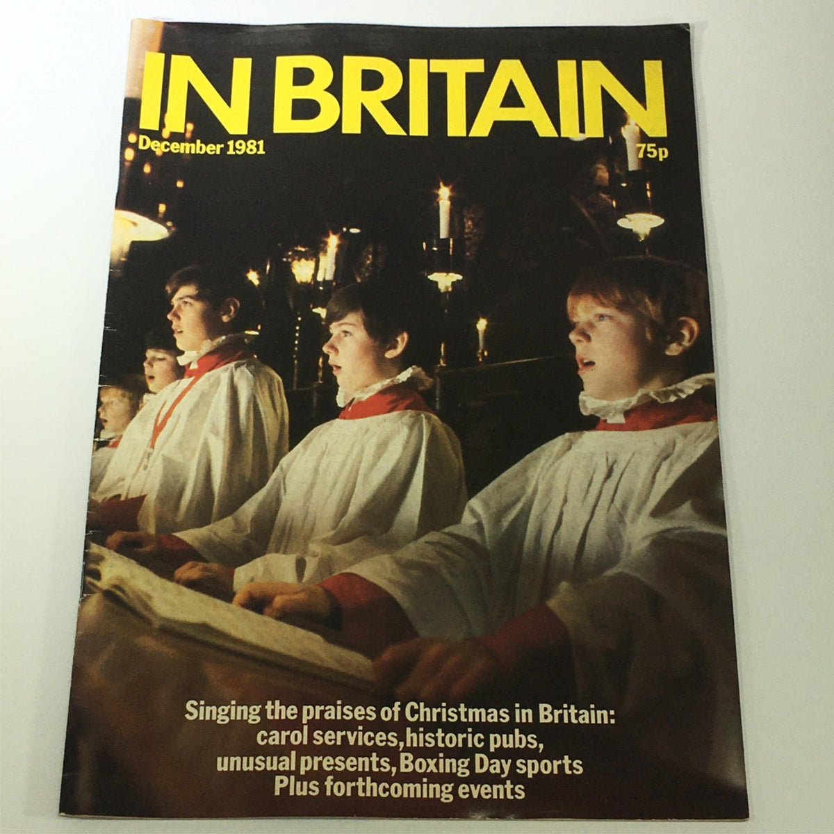 Cover of the December 1981 issue of In Britain magazine featuring a choir performing during a Christmas service, highlighting the theme 'Singing the Praises of Christmas in Britain'. The magazine showcases holiday traditions alongside details about carol services, historic pubs, and Boxing Day events.