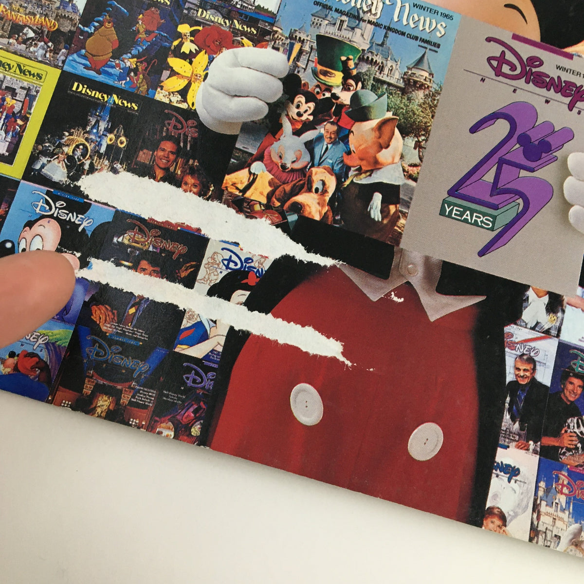Close-up of Disney News Magazine Winter 1990 cover showing Mickey Mouse holding the magazine, with visible wear and a collage of Disney characters and movie titles in the background.