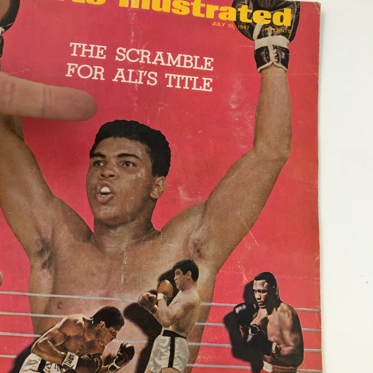 Close-up of the cover of Sports Illustrated Magazine from July 10, 1967, highlighting the title 'The Scramble for Ali's Title'. Muhammad Ali is depicted with raised arms, with additional boxing imagery in the background.