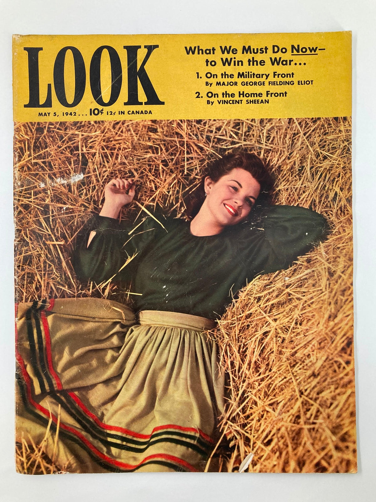 Cover of VTG Look Magazine from May 5, 1942 featuring model Phyllis Forbes in a green blouse and skirt, lying in a field of straw. This vintage magazine showcases fashion and culture from the 1940s.