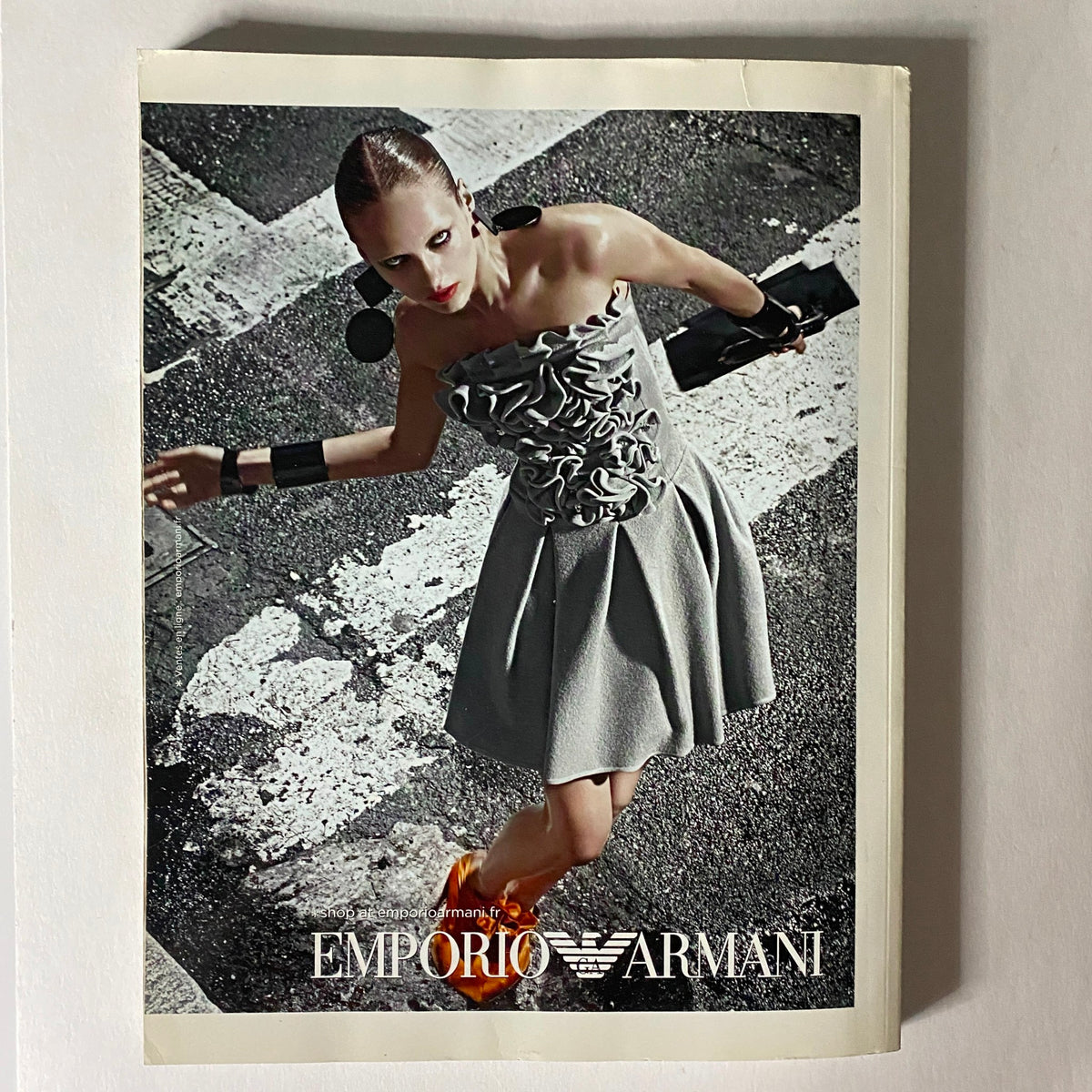 Emporio Armani advertisement from Numéro Magazine September 2010 No. 116, depicting a model in a fashionable dress on the street.