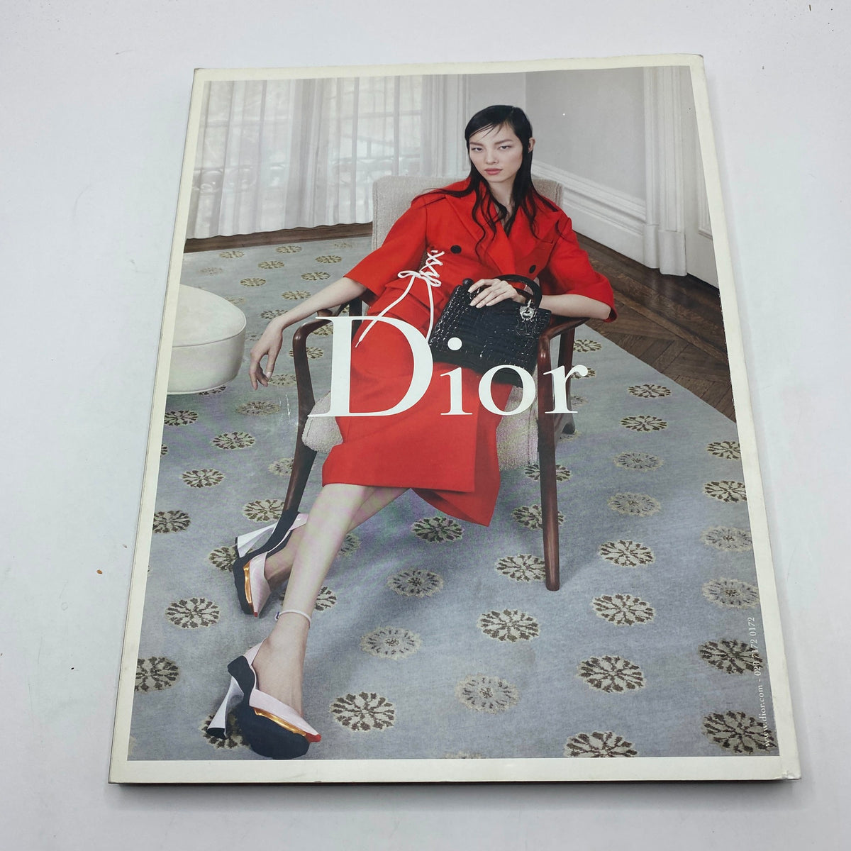 Fashion advertisement from i-D Magazine Fall 2014 No. 333 featuring a model dressed in red by Dior, seated in a well-decorated room.