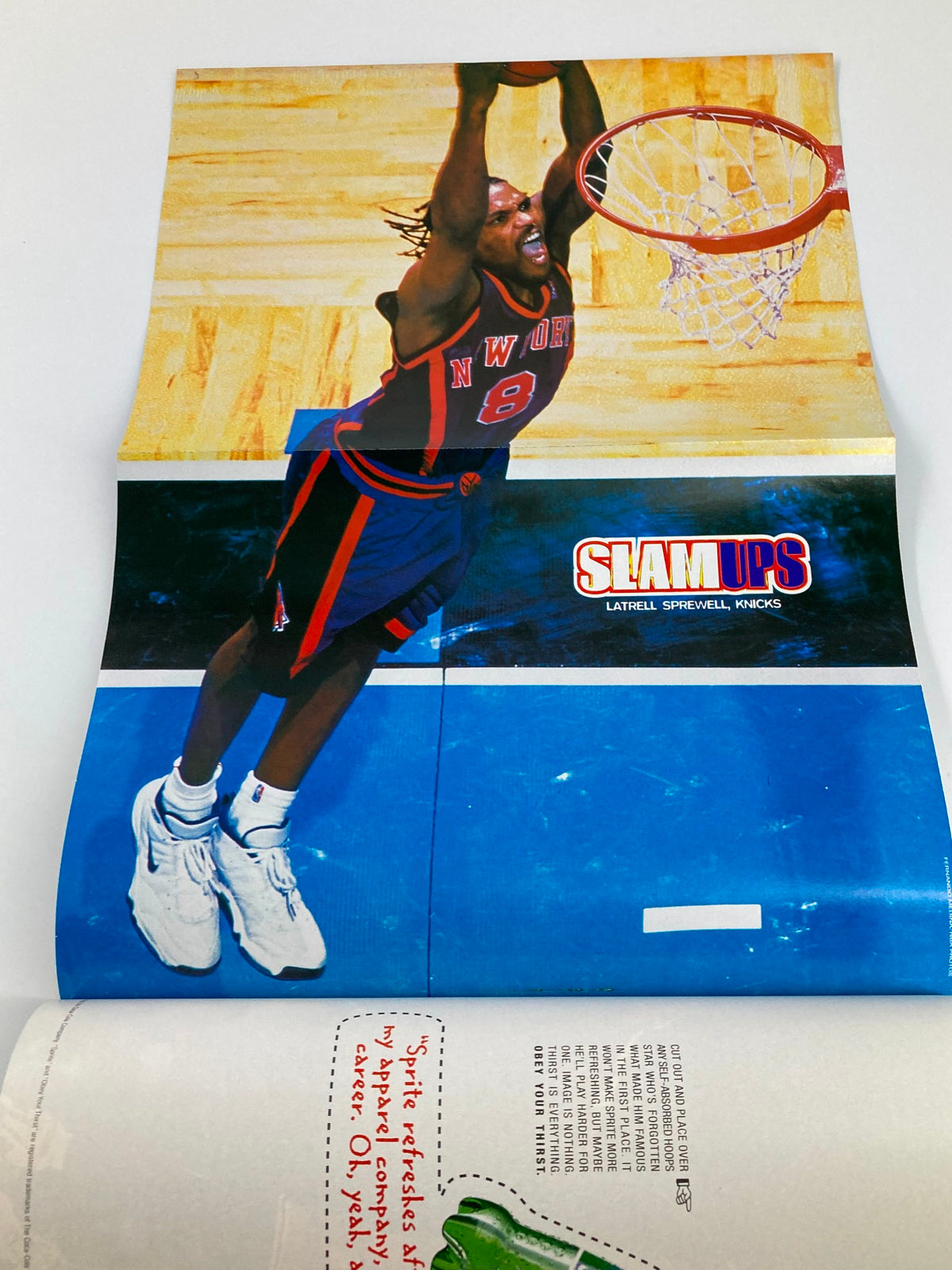 Poster image from Slam Magazine June 1999 featuring NBA player Latrell Sprewell of the New York Knicks, showcasing his dynamic dunking pose. This collectible magazine highlights Shaquille O'Neal on the cover and includes the iconic poster as part of its content, perfect for basketball fans and memorabilia collectors.
