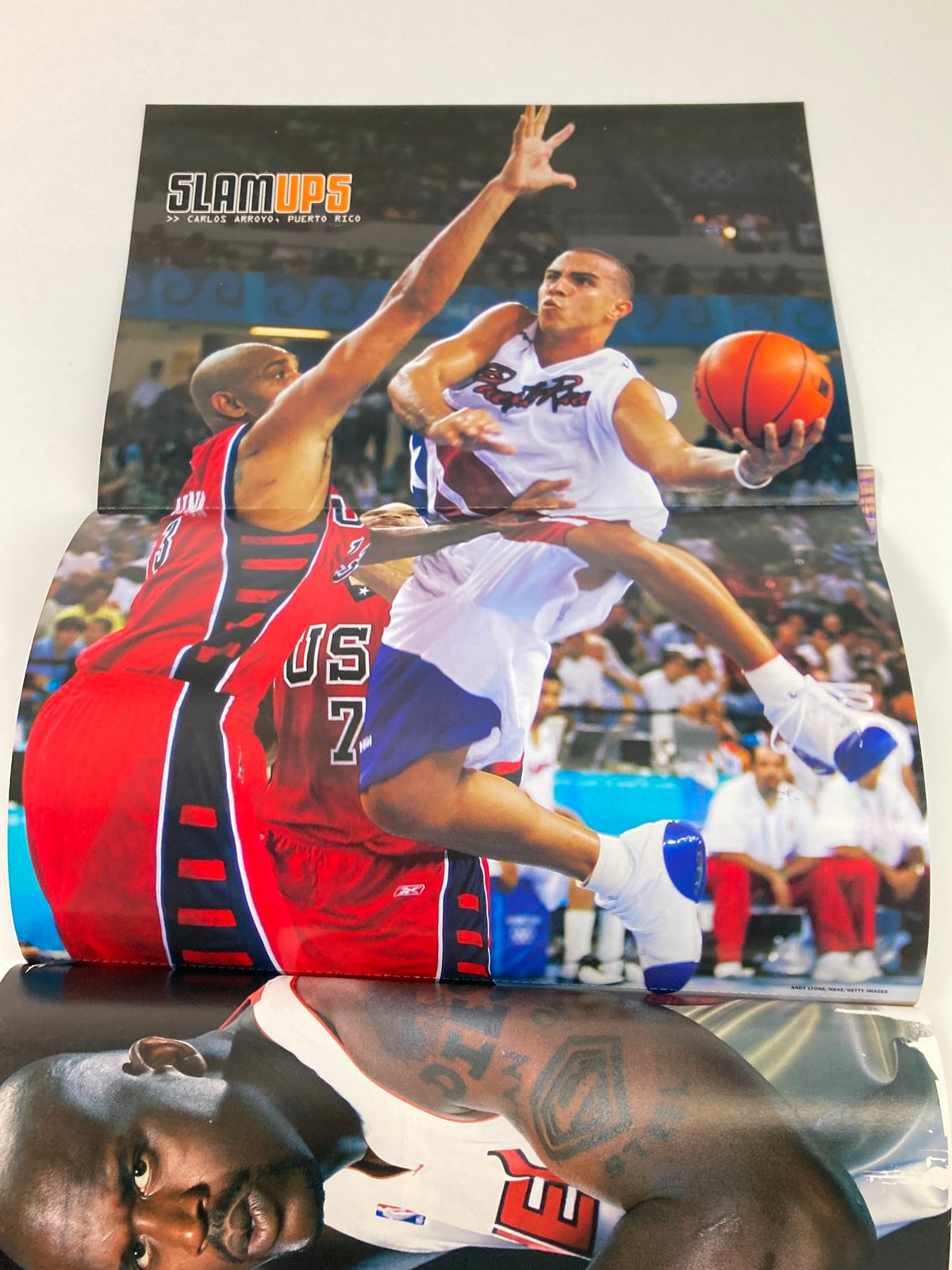 Poster included in Slam Magazine November 2004 depicting a dynamic basketball play, highlighting the excitement of the NBA and featuring athletes from the era.