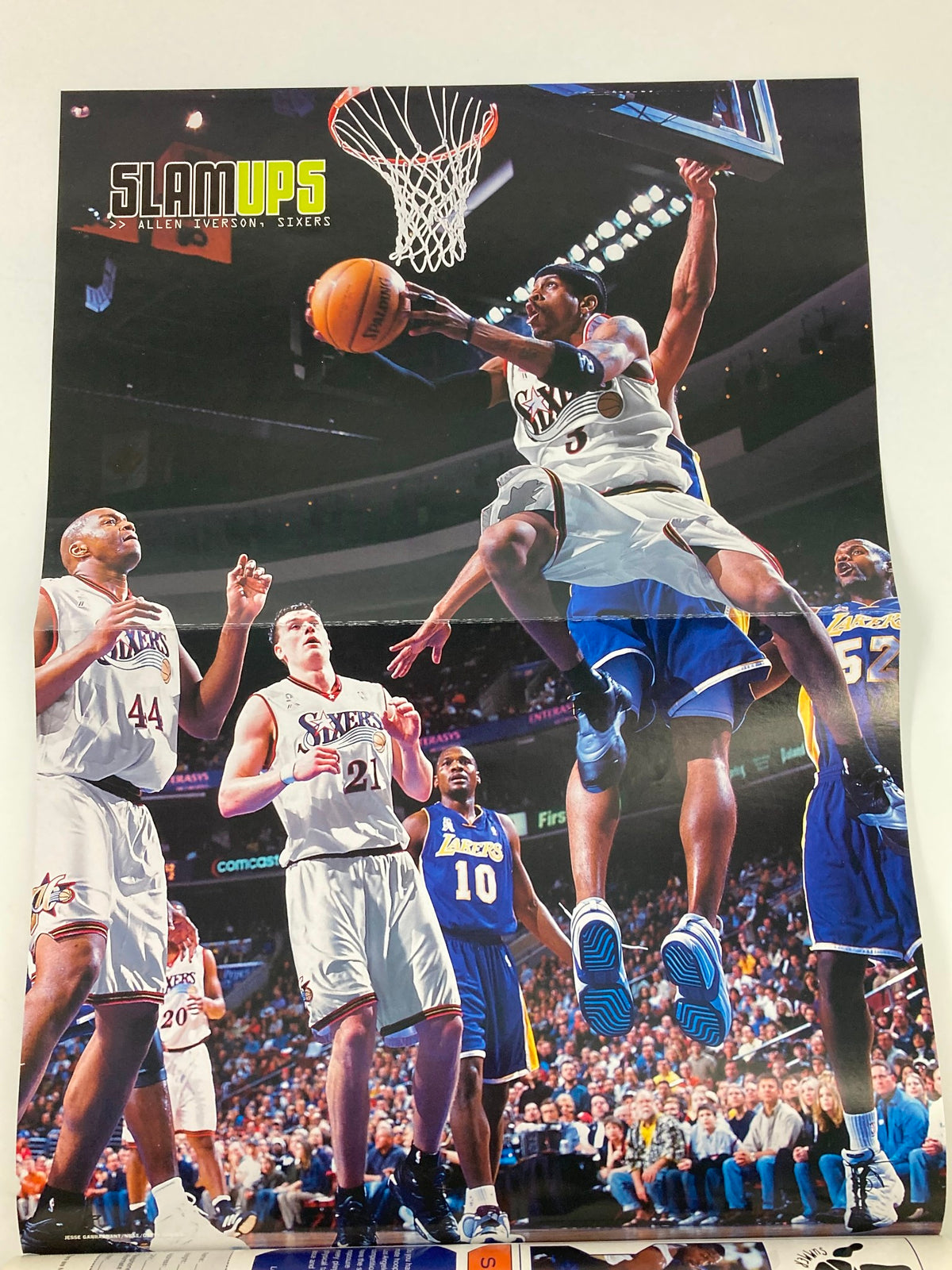 Poster from Slam Magazine June 2002 displaying a basketball player in action during a game. This vibrant image adds to the collectible nature of the magazine featuring the iconic Dirk Nowitzki.