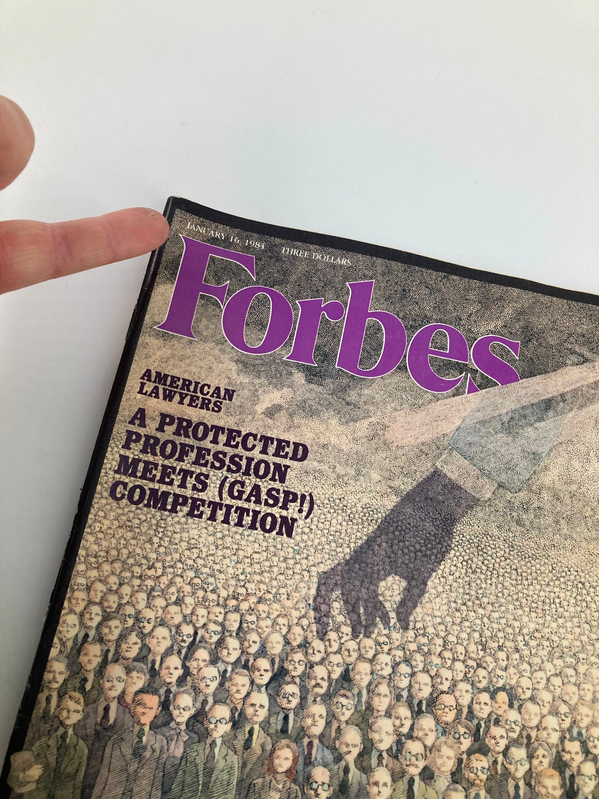 Close-up view of the Forbes Magazine cover dated January 16, 1984, titled 'A Protected Profession Meets Competition.' The image shows a person pointing at the title, emphasizing the date and the theme of competition among American lawyers.