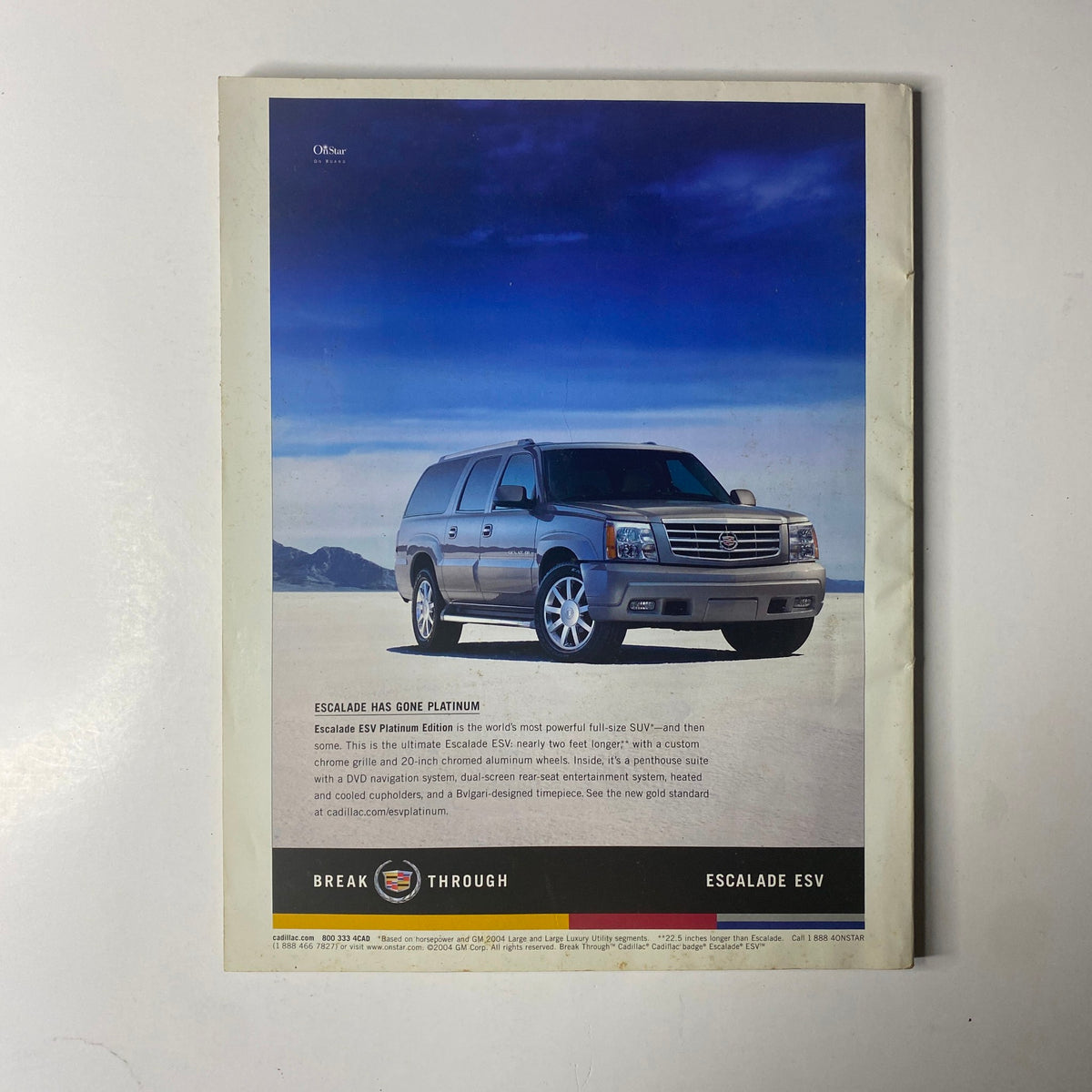Advertisement for the Cadillac Escalade ESV, featuring a sleek silver SUV against a scenic blue sky backdrop, showcasing its luxury and power. This image corresponds with the title 'Ebony Magazine August 2004 Halle Berry Cover'.