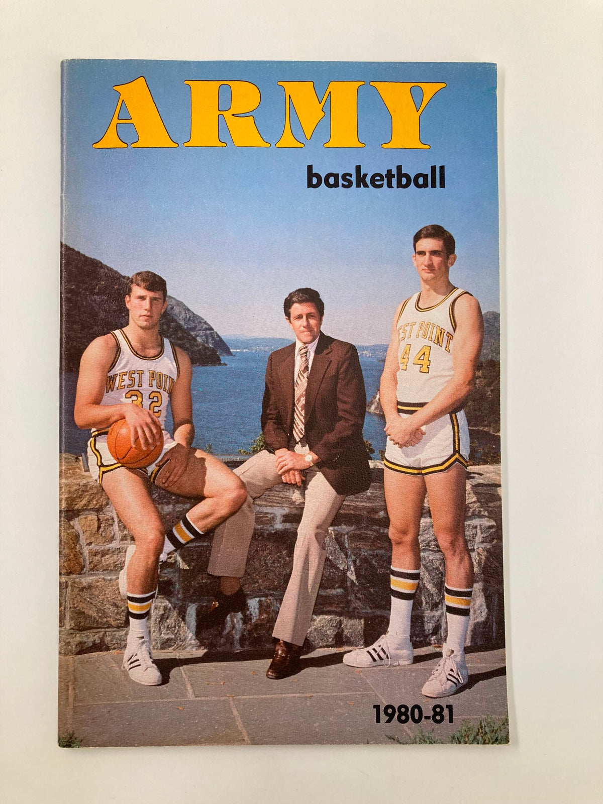 Cover of the 1980-1981 NCAA U.S. Military Academy Army Basketball Guide featuring two basketball players in uniforms and a coach, showcasing the iconic West Point backdrop.