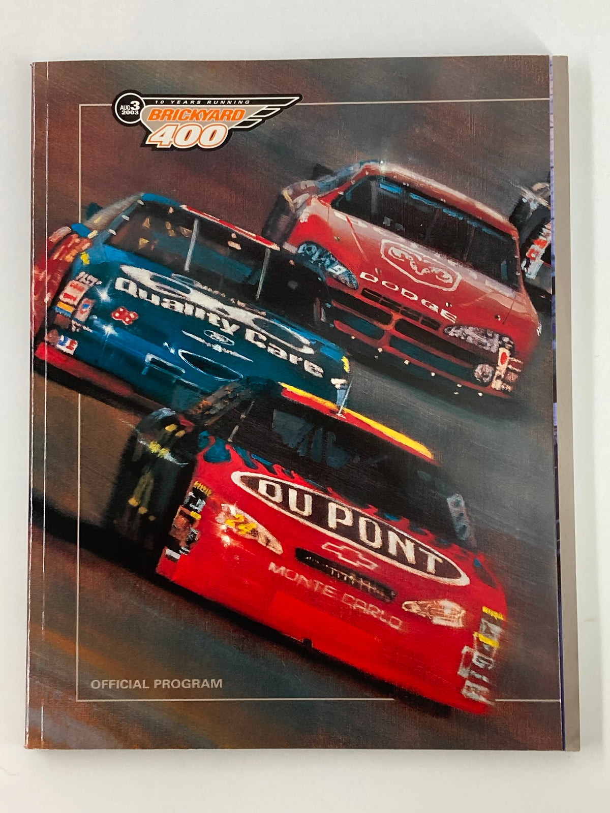 August 3 2003 NASCAR 10 Years Running Brickyard 400 Official Program cover featuring vibrant illustrations of racing cars on the track, highlighting the excitement of NASCAR events.