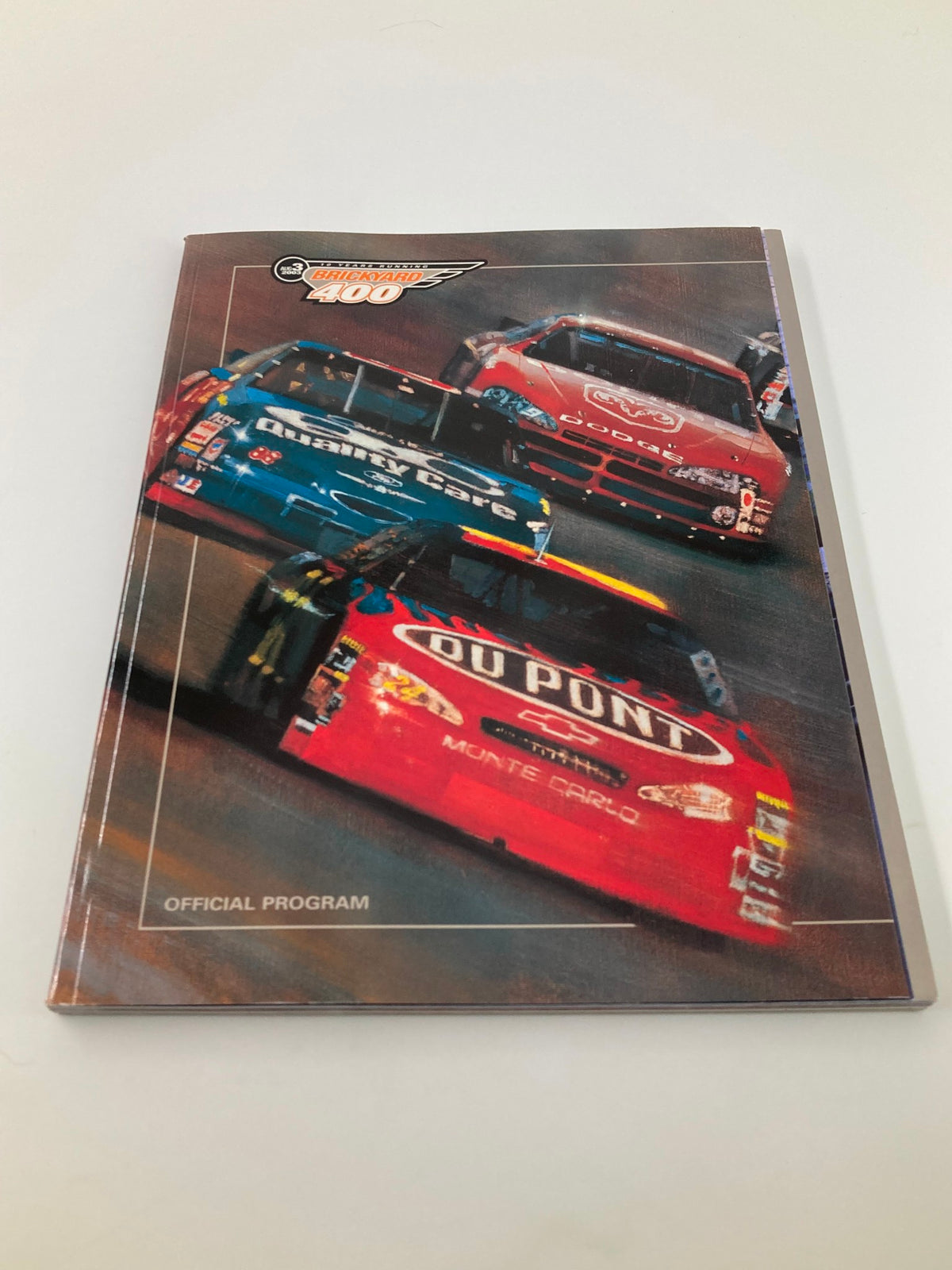 Cover of the August 3 2003 NASCAR 10 Years Running Brickyard 400 Official Program featuring racing cars.