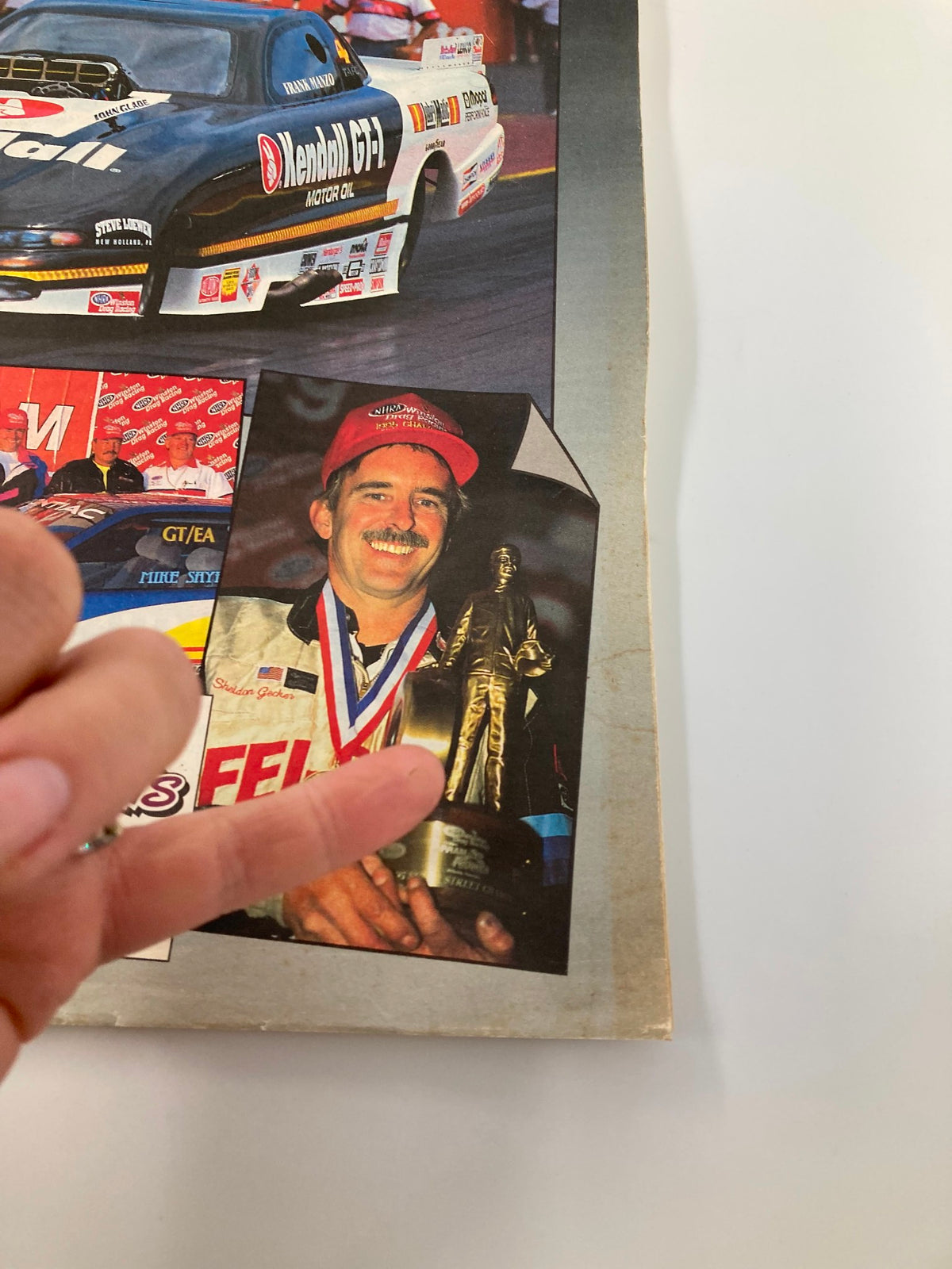 Detail from the National Dragster Magazine May 12, 1995, showcasing a racer holding a trophy, symbolizing victory in the drag racing community.