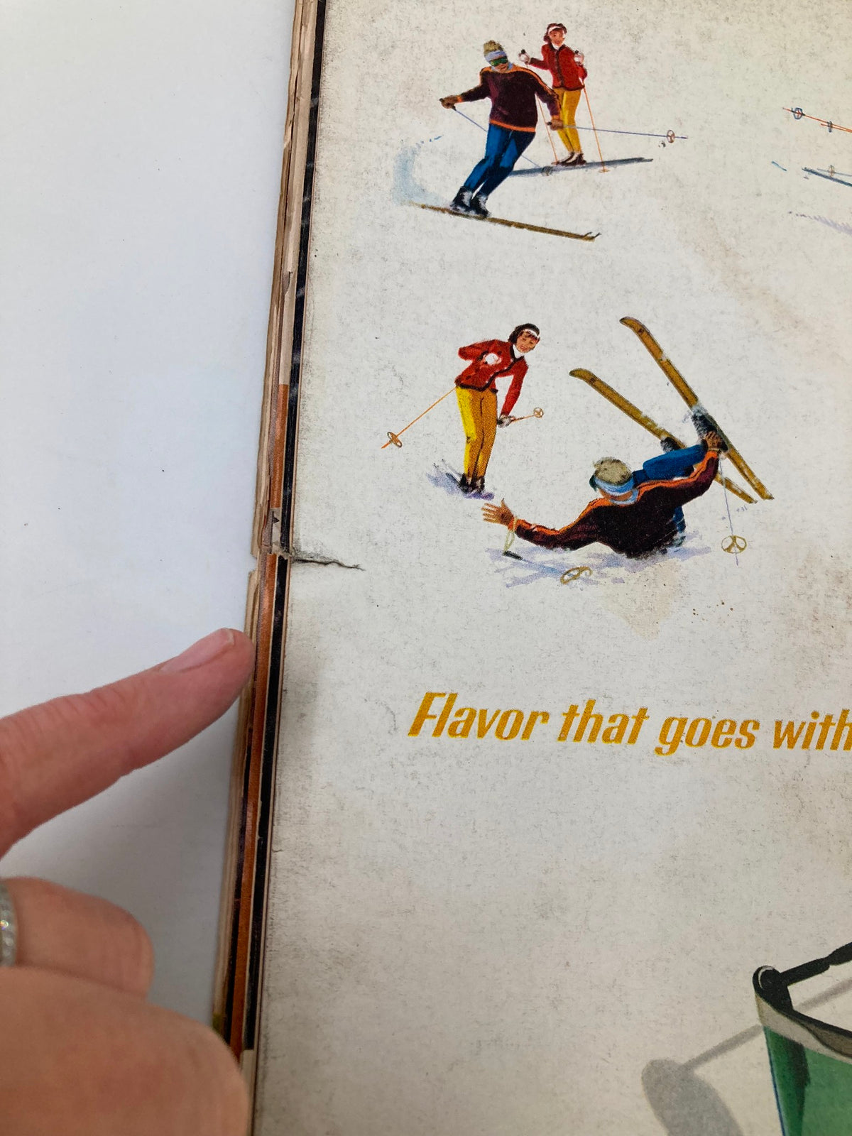Close-up of the spine of VTG Life Magazine February 21, 1964 with visible wear, showcasing illustrations related to skiing, adding historical context to the magazine's era.