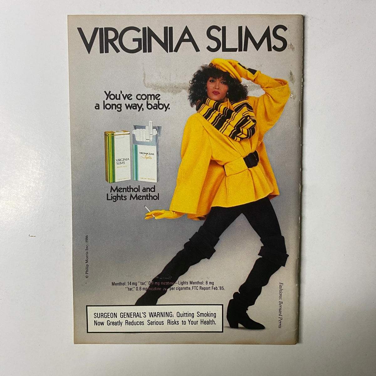 Vintage advertisement for Virginia Slims featuring a stylish model in a bright yellow coat, promoting the slogan 'You've come a long way, baby.' This image is included in Jet Magazine, December 8, 1986, with Marilyn McCoo on the cover, Vol. 71, No. 12.