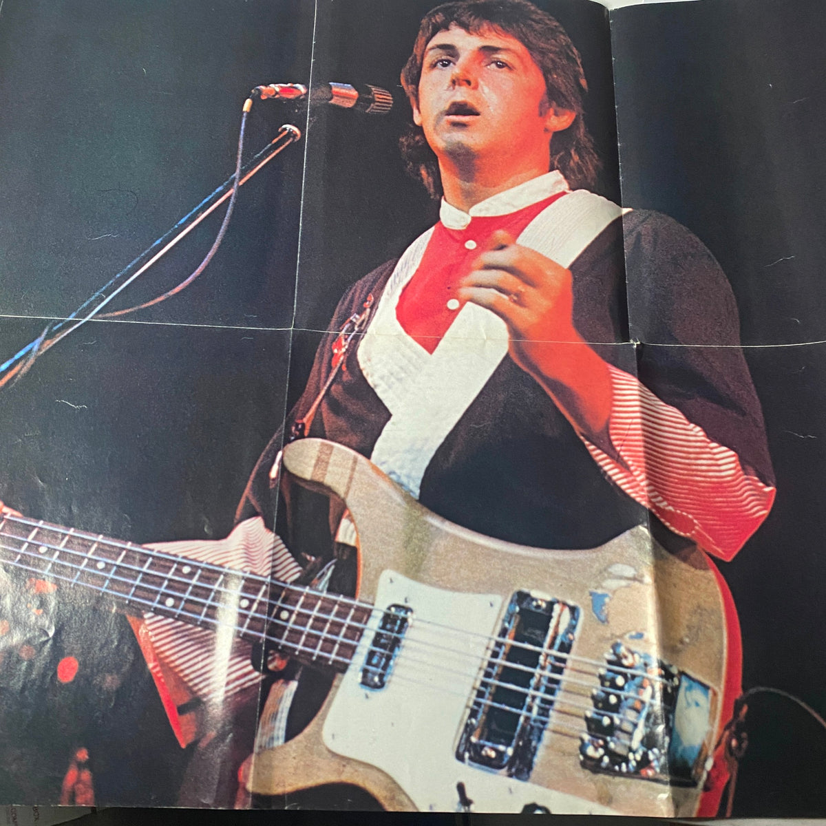 Centerfold image of Paul McCartney performing live in the Rock Superstars Poster Magazine 1975 No. 7, showcasing his musical talent during the Wings era.