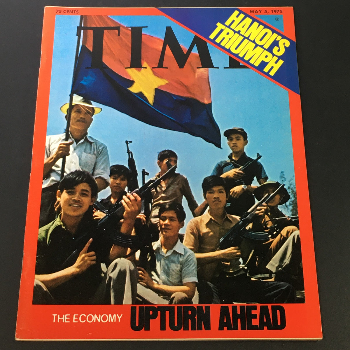 Vintage Time Magazine May 5, 1975 cover featuring a group of individuals holding weapons and a flag, with the title 'The Economy Upturn Ahead' and the text 'Hanoi's Triumph' prominently displayed.