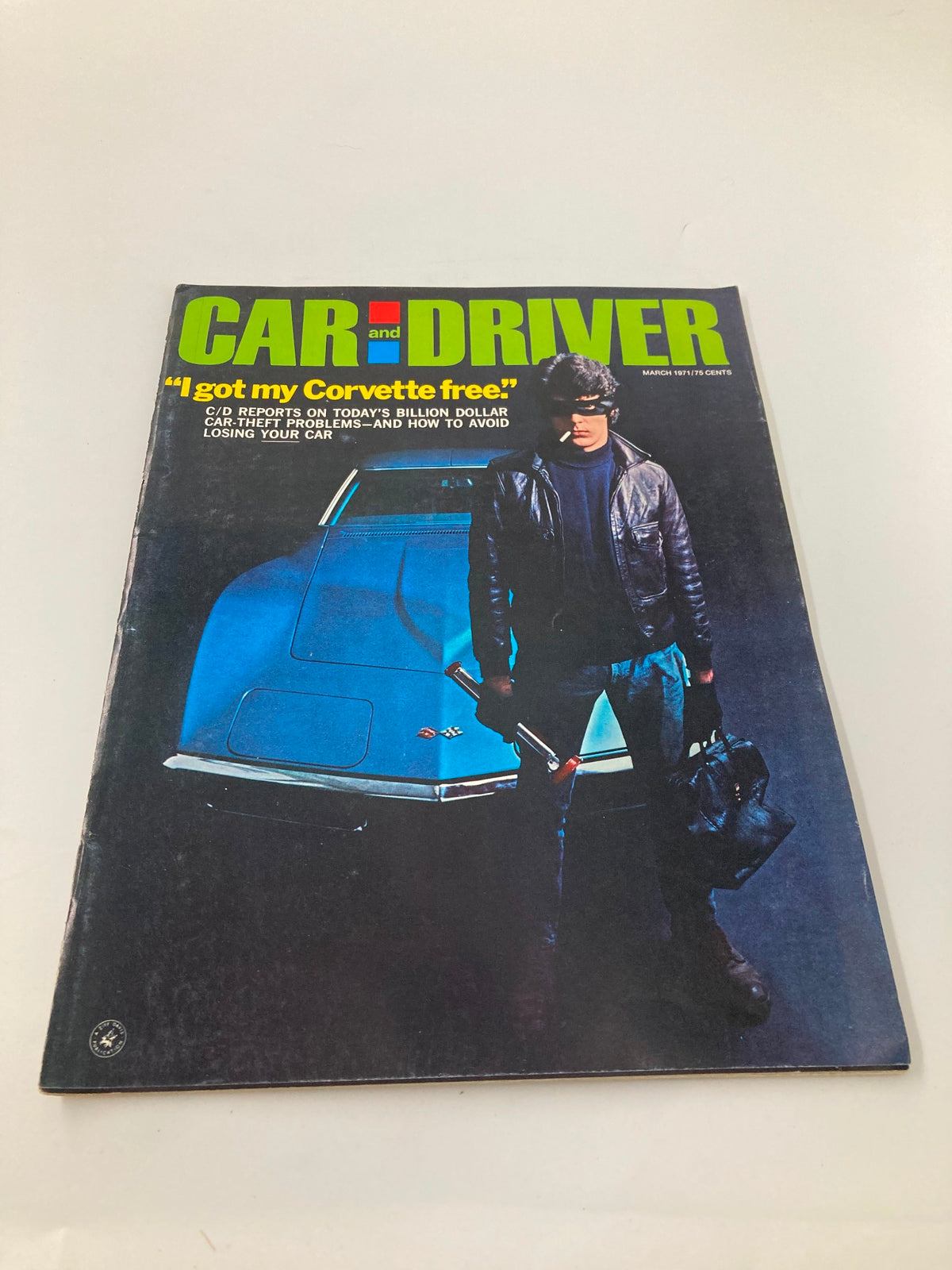Front cover of Car and Driver Magazine, March 1971 edition, displaying the headline 'I got my Corvette free', depicting a person with a crowbar in front of a blue Corvette.