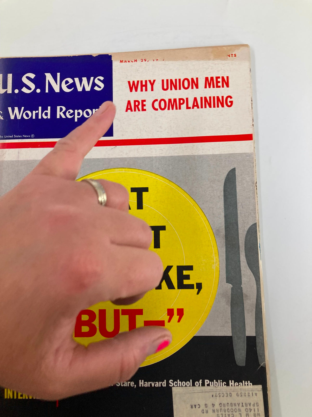 Close-up of the cover of US News & World Report Magazine from March 29, 1957, highlighting the section 'Why Union Men Are Complaining' and a hand pointing at the title. The design includes a striking yellow circle and utensils.