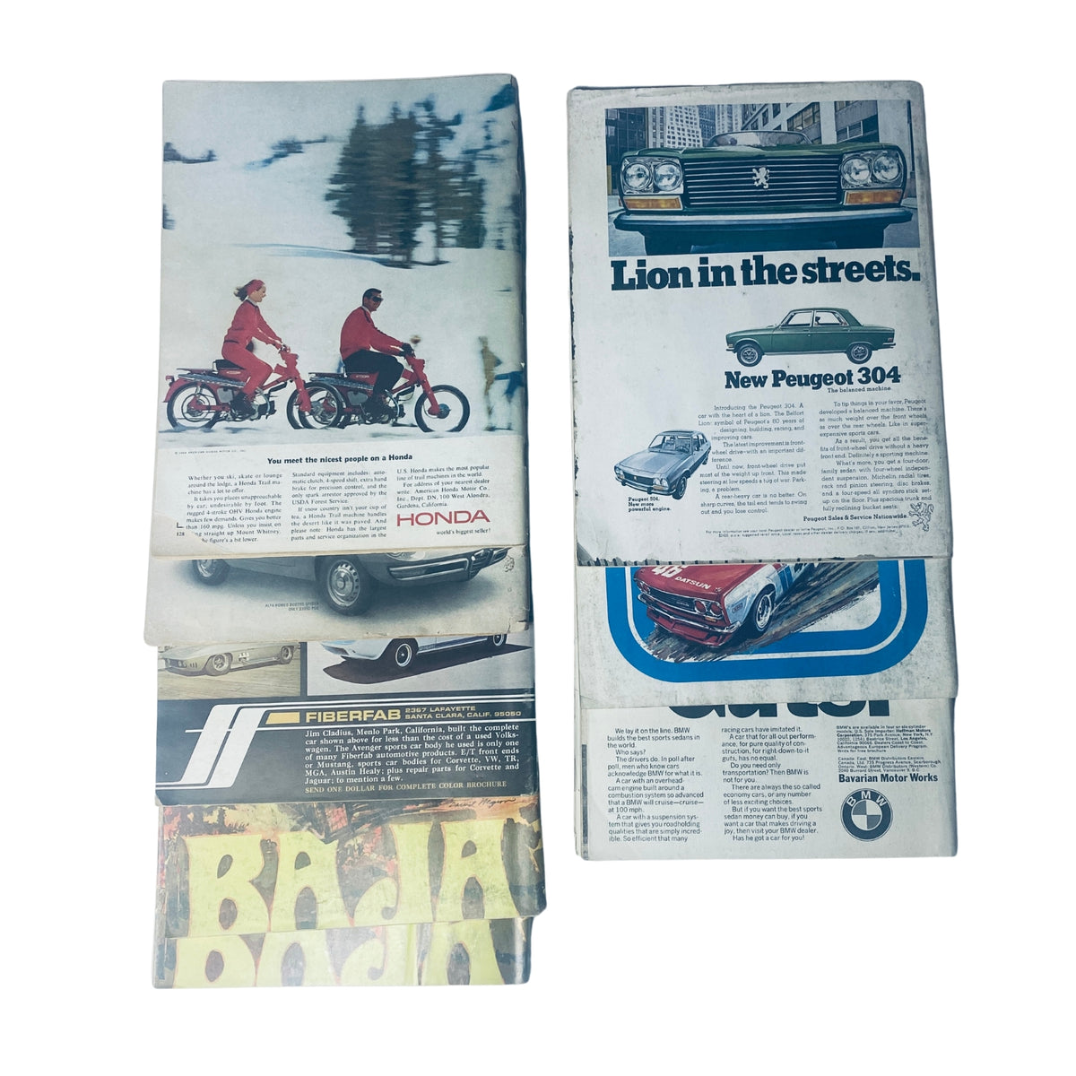 Stack of vintage advertisements from the Lot of 8 Road & Track Road Test Annuals 1965–1973, highlighting classic cars and motorbikes.