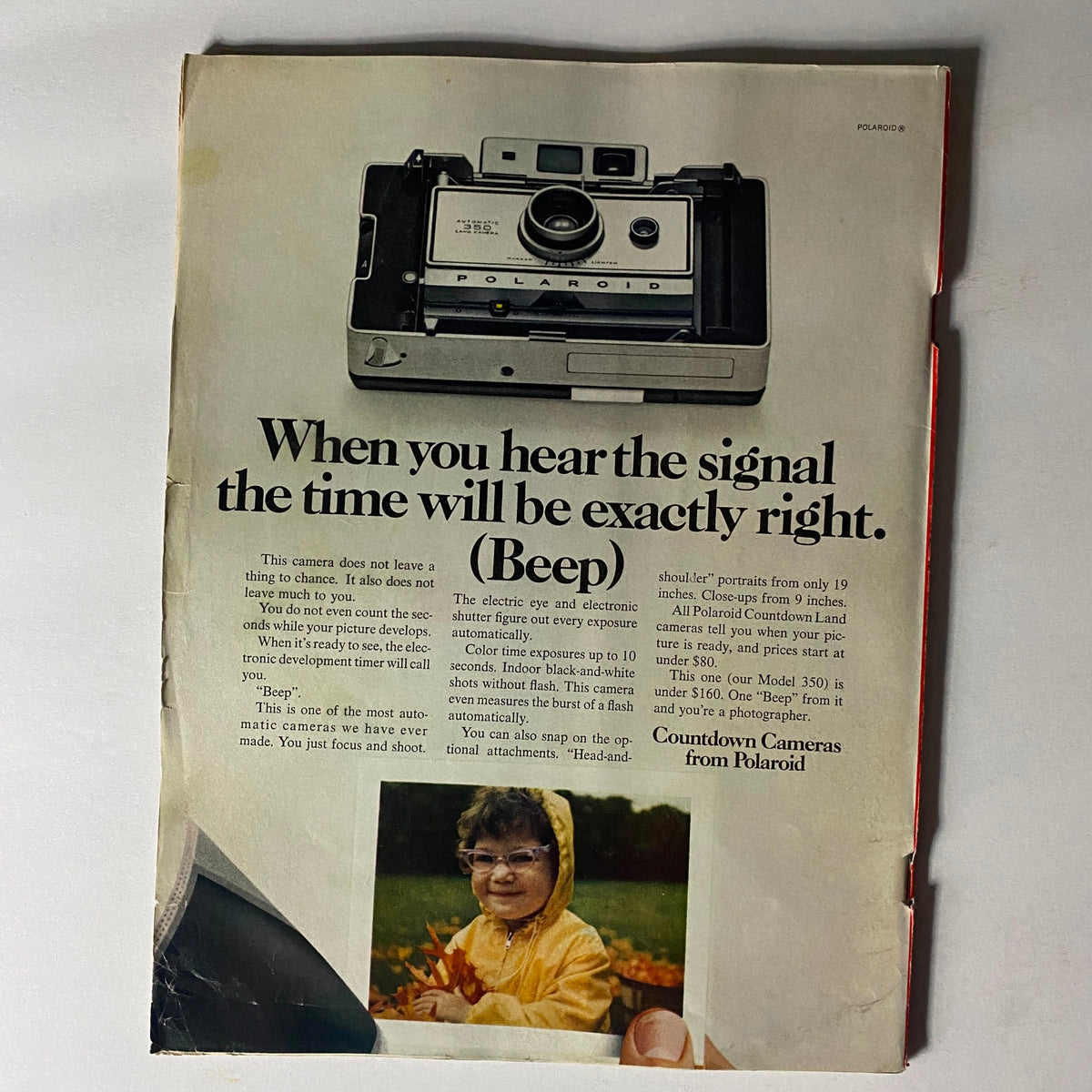 A vintage advertisement from a 1970 Time Magazine featuring a Polaroid camera. The ad emphasizes the camera's features, including electronic shutter control and color exposure precision. Accompanying the text is an image of a child in a yellow raincoat with glasses, playing with fall leaves. This ad illustrates the photography technology of the era, along with a playful appeal to potential customers.