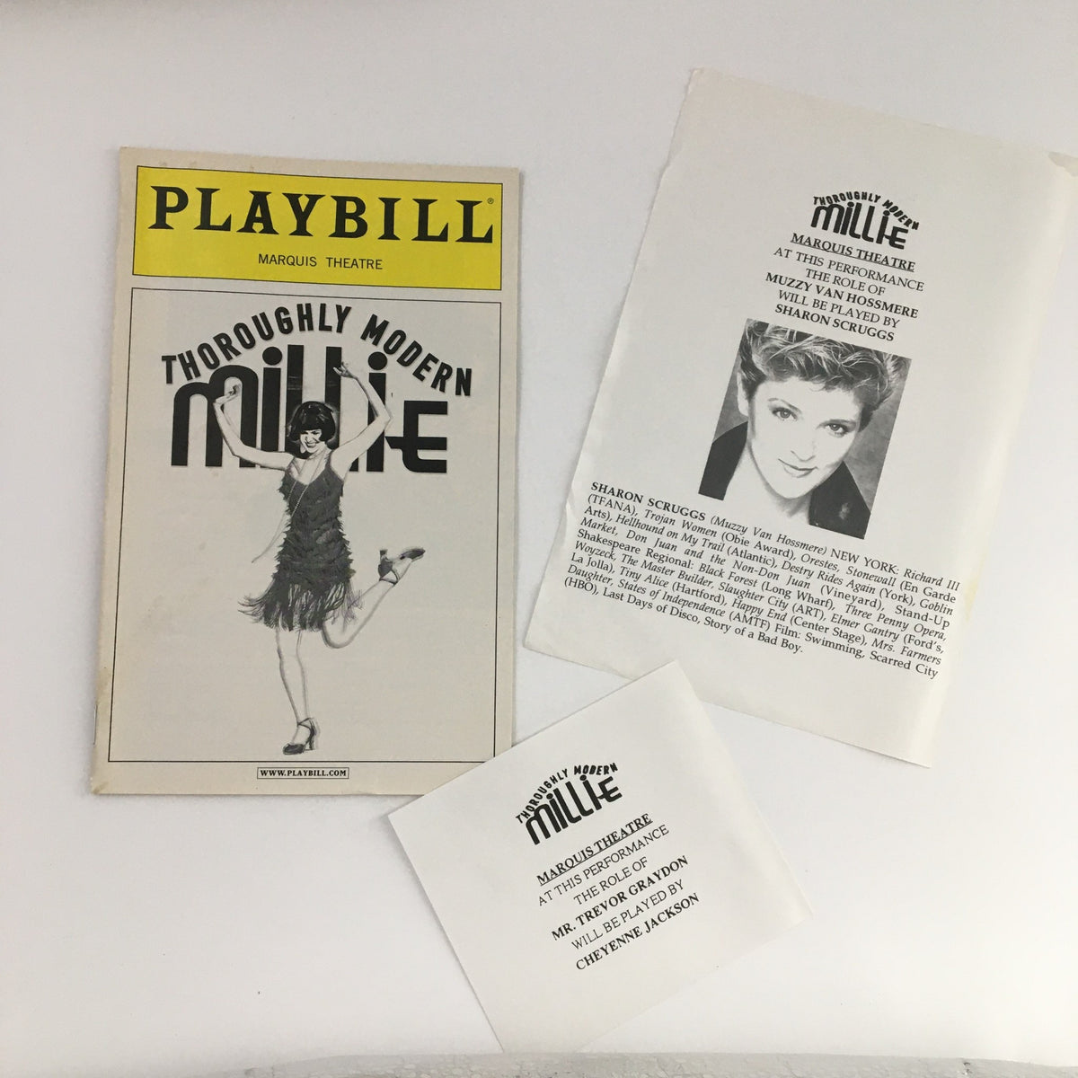 2002 Thoroughly Modern Millie Playbill featuring the iconic cover design, showcasing the title in bold letters and an illustration of the lead character. Includes original paperwork and details about the production.