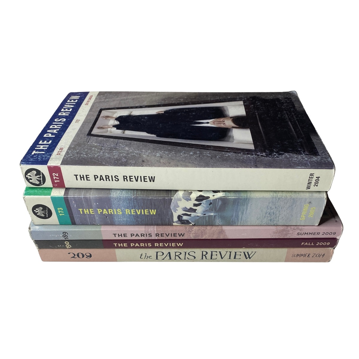 A stack of The Paris Review Magazine Lot of 5 from the 2000s, highlighting the Winter 2004, Spring 2005, Summer 2009, Fall 2009, and Summer 2014 issues. Each magazine showcases unique artwork and thematic elements reflecting the literary content.