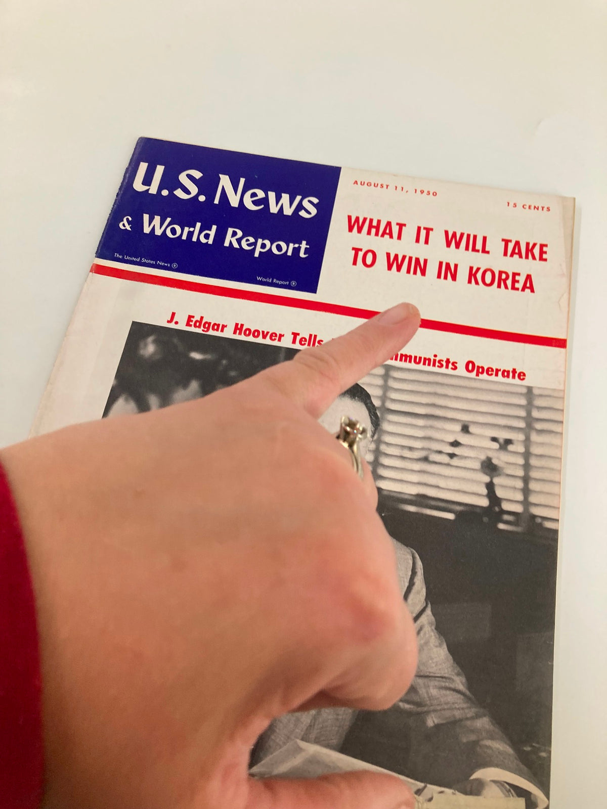 Close-up view of the US News & World Report Magazine cover from August 11, 1950, with a hand pointing at the headline 'What It Will Take to Win in Korea' and J. Edgar Hoover's name.