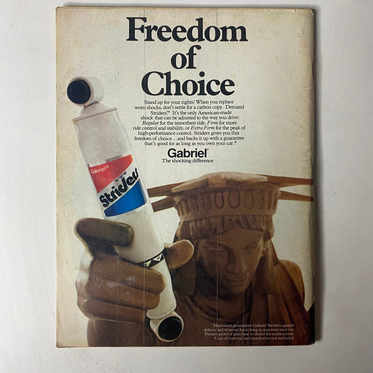 Advertisement in Car Craft Magazine May 1973 for Gabriel Strider shocks, featuring a dramatic image of a hand holding the shock against a background of the Statue of Liberty.