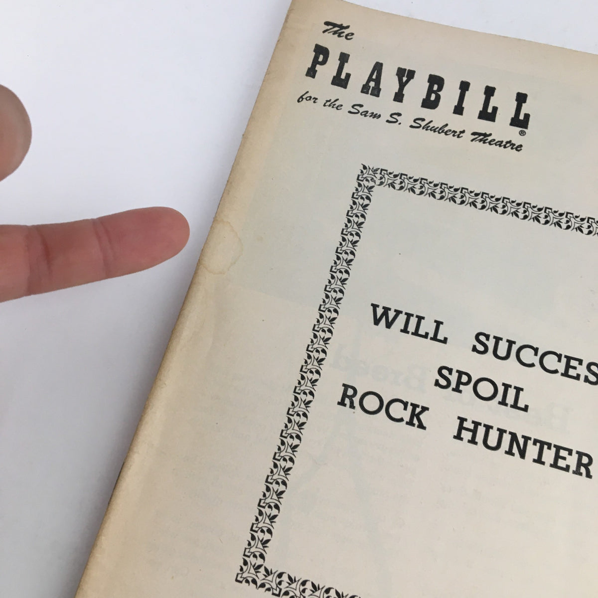 Close-up of the 1956 Playbill cover for the Sam Shubert Theatre, showing the title 'Will Success Spoil Rock Hunter?' with a hand pointing at it.