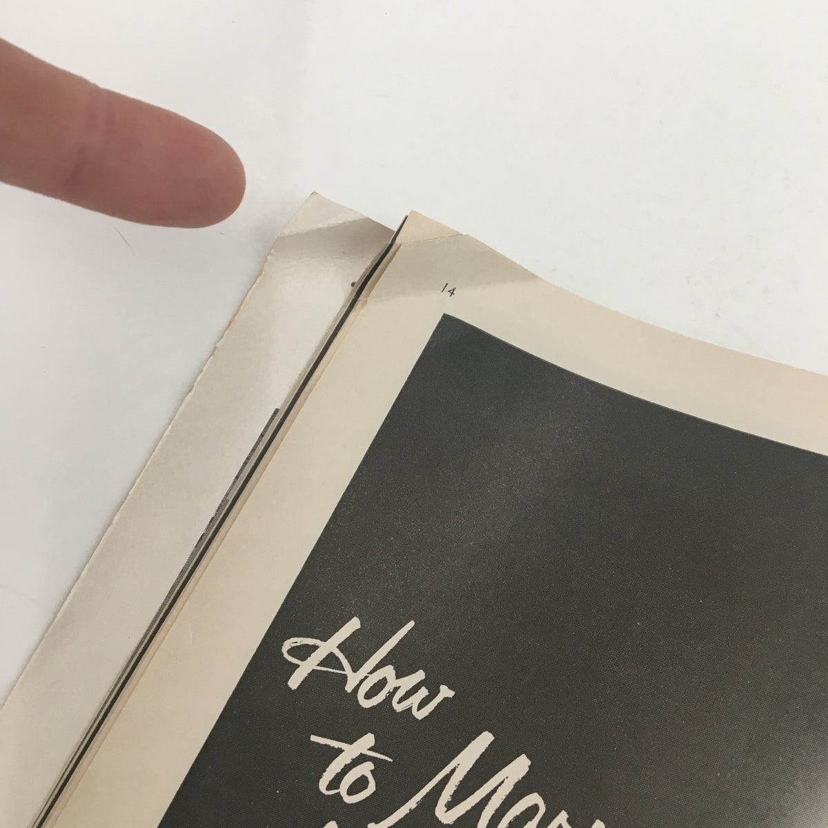 Close-up image showing a corner of the 1957 Playbill for Romanoff and Juliet, featuring a finger pointing at a crease on the page.