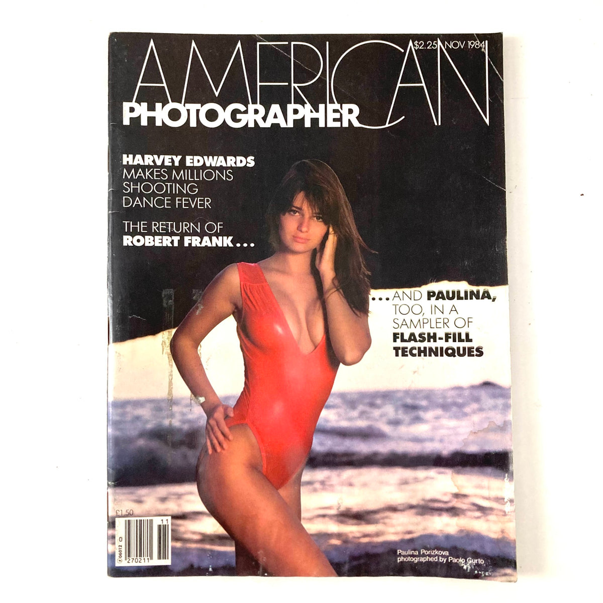 Cover of American Photographer Magazine November 1984 featuring Paulina Porizkova in a red swimsuit at the beach, highlighting photography and modeling from that iconic era.