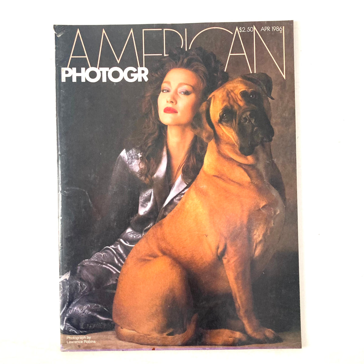 Cover of American Photographer Magazine April 1986 featuring a woman in a silver outfit and a dog, showcasing photography by Lawrence Robins.