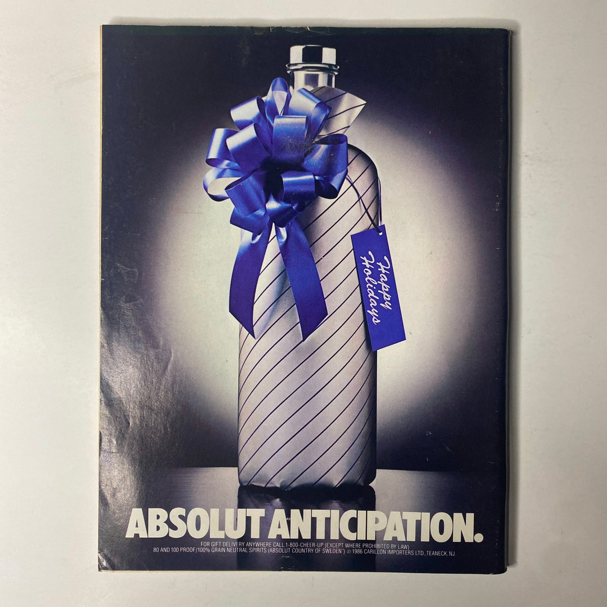 Back cover of Forbes Magazine December 15, 1986, displaying a minimalist design featuring a bottle wrapped in a bow with the text 'Absolut Anticipation' and a festive holiday tag.