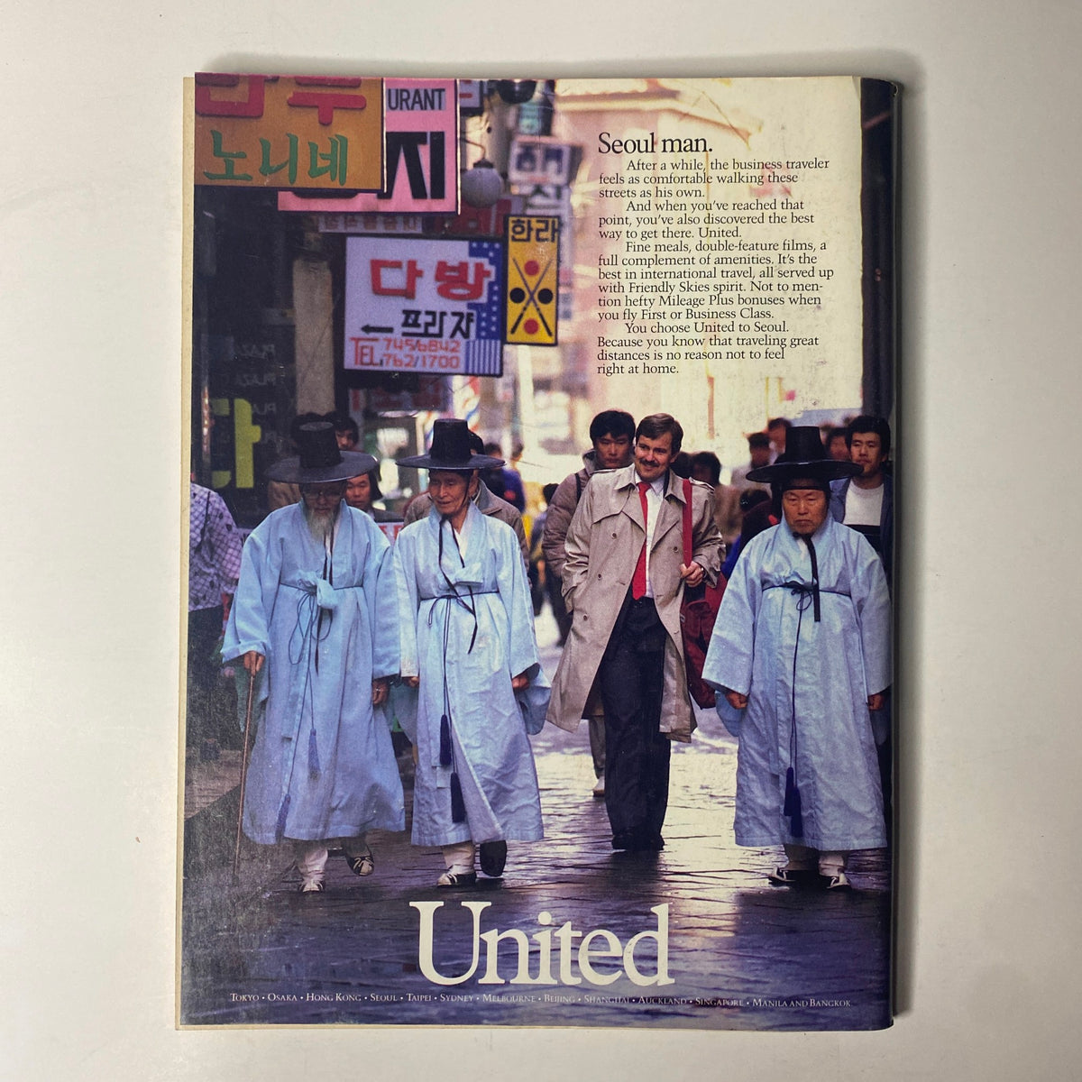 Forbes Magazine October 19, 1987 United Airlines advertisement featuring a businessman walking through Seoul, South Korea. The advertisement emphasizes comfort in travel and the experience provided by United Airlines.