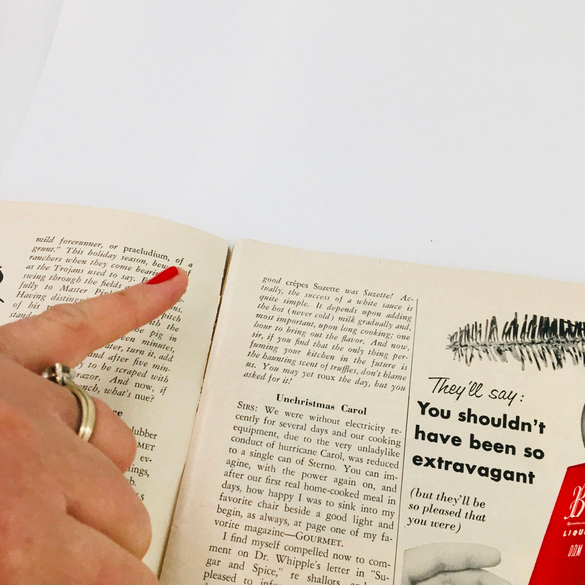 Inside page of Gourmet Magazine December 1954 Vol 14 #12 showing a hand pointing at the text, highlighting recipes and culinary tips from the era.